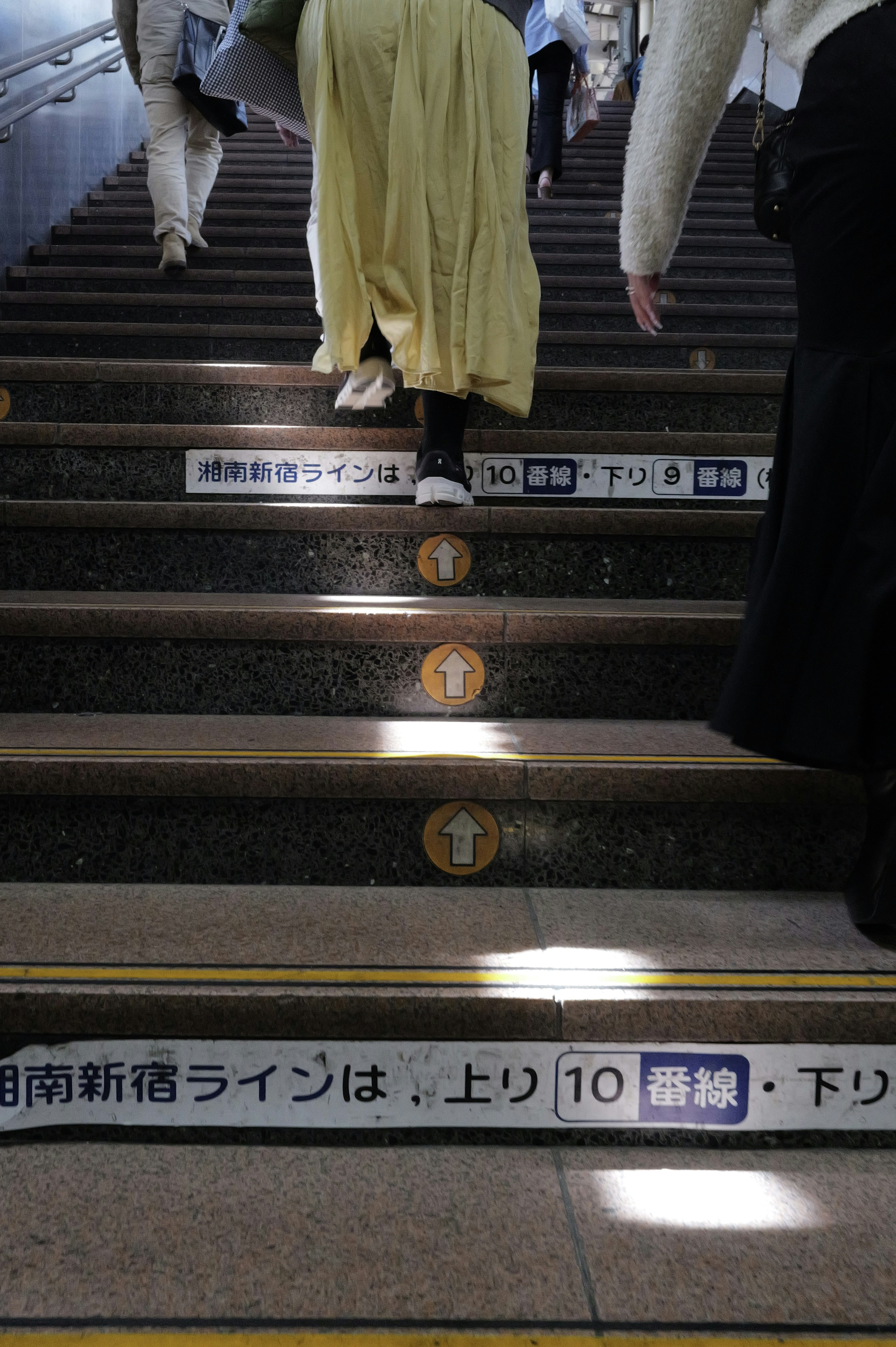 階段を上る人々の画像 駅の階段に印刷された指示とマーク