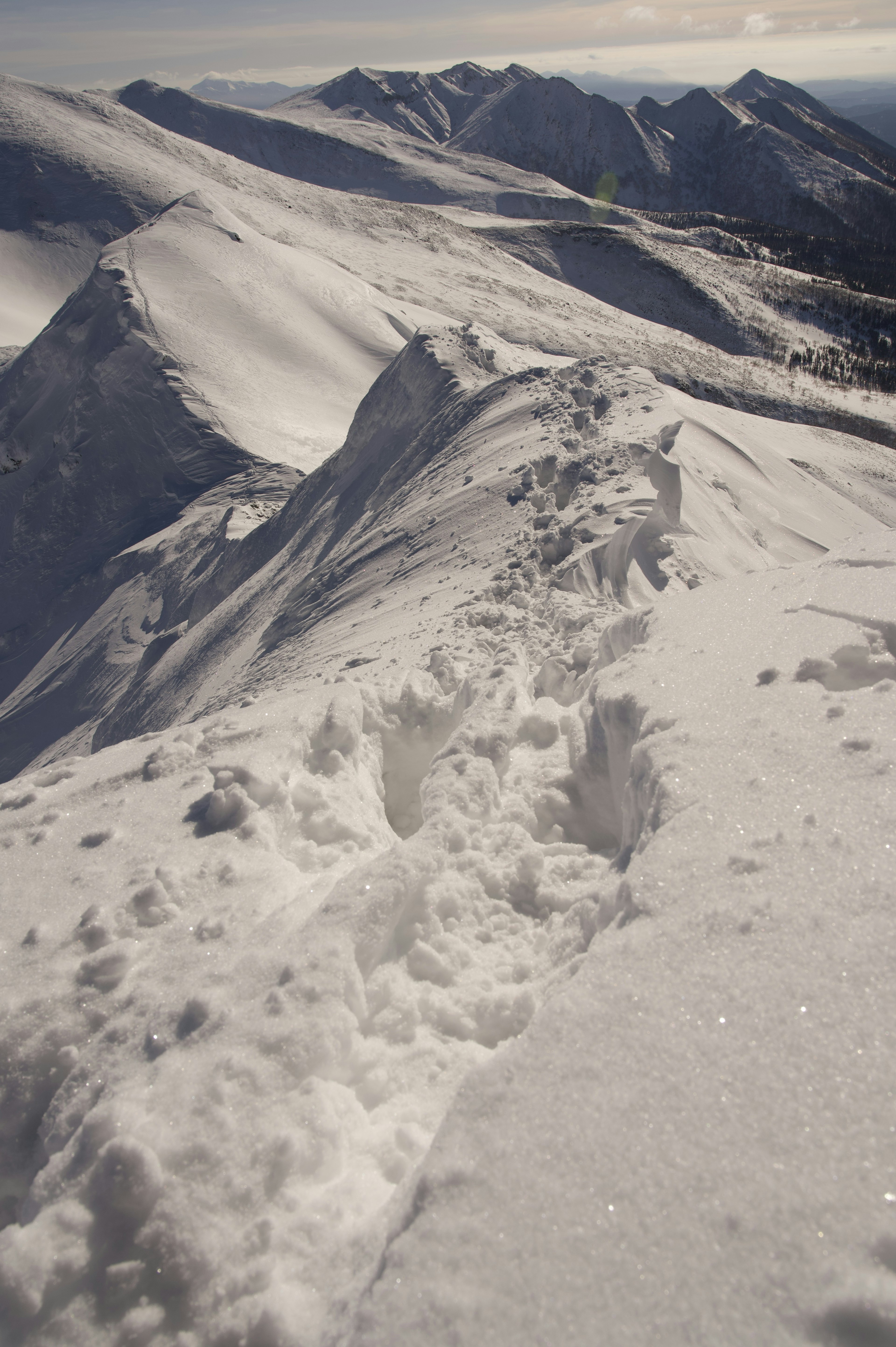 Vista escénica de un pico montañoso cubierto de nieve con huellas en la nieve