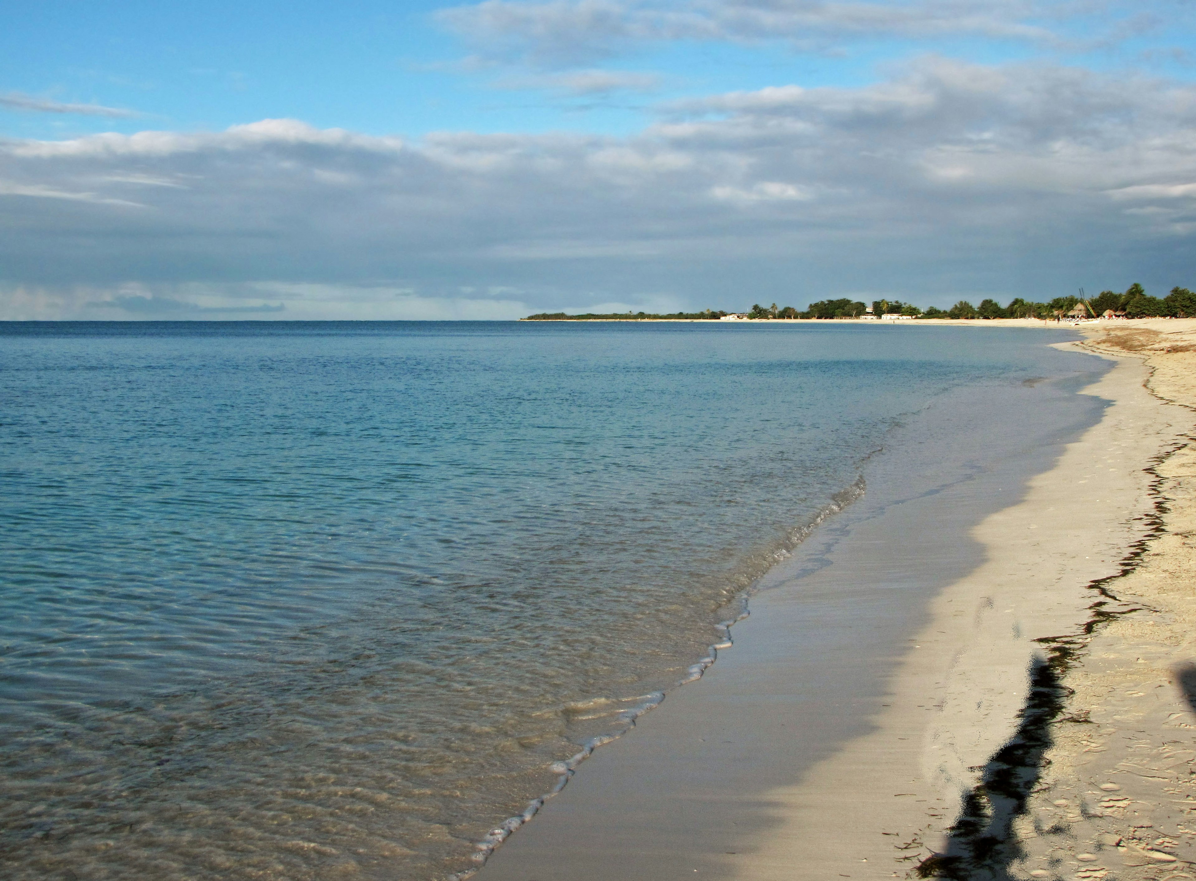 Paesaggio di mare calmo e spiaggia di sabbia bianca con cielo blu e nuvole