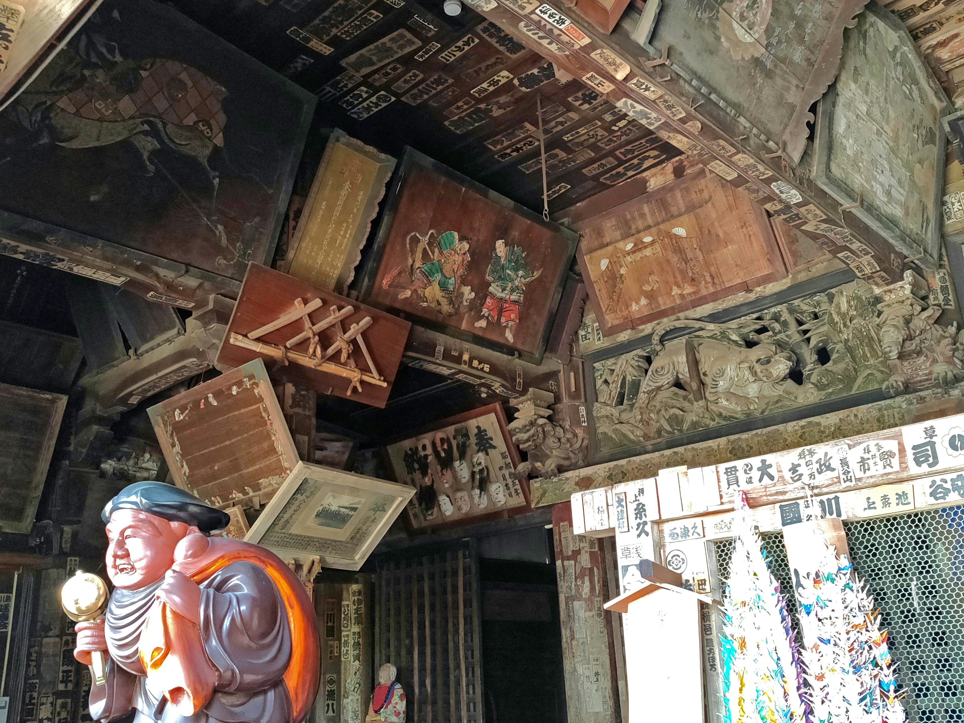 Interior de un antiguo templo con estatua de madera decorativa y pinturas en el techo