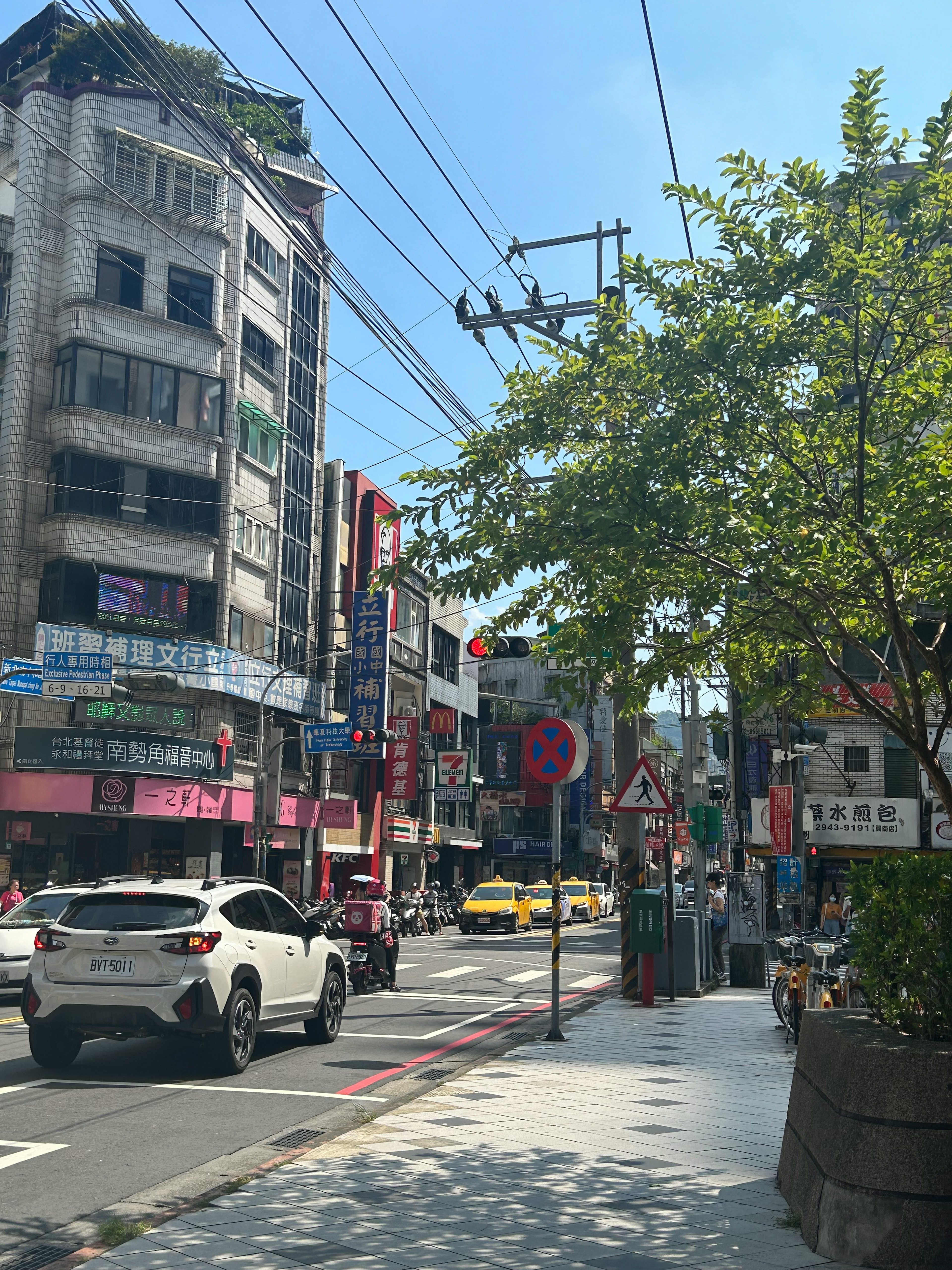 Bustling street scene with buildings and clear blue sky cars and sidewalks