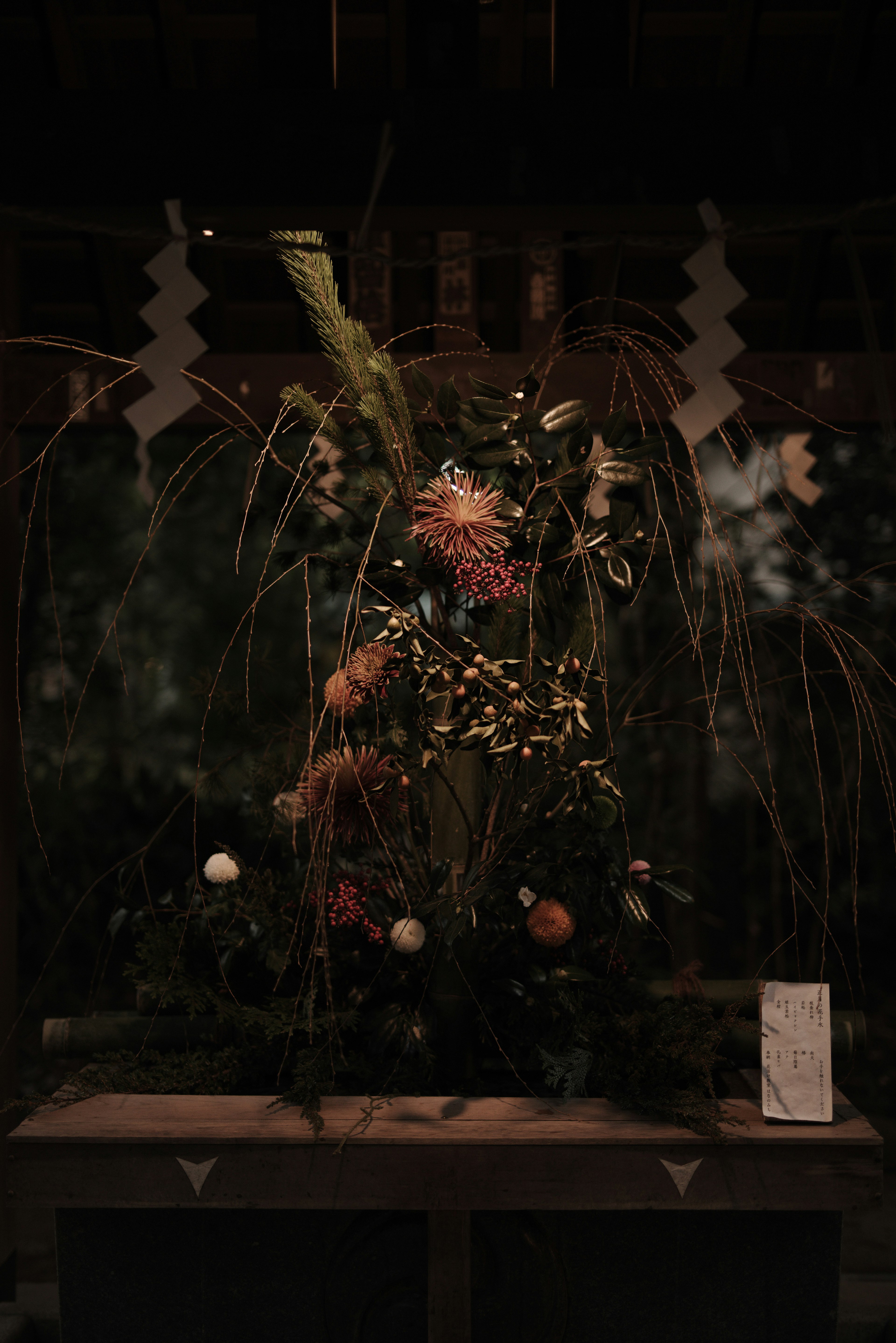 A floral arrangement featuring vibrant flowers and grasses against a dark background