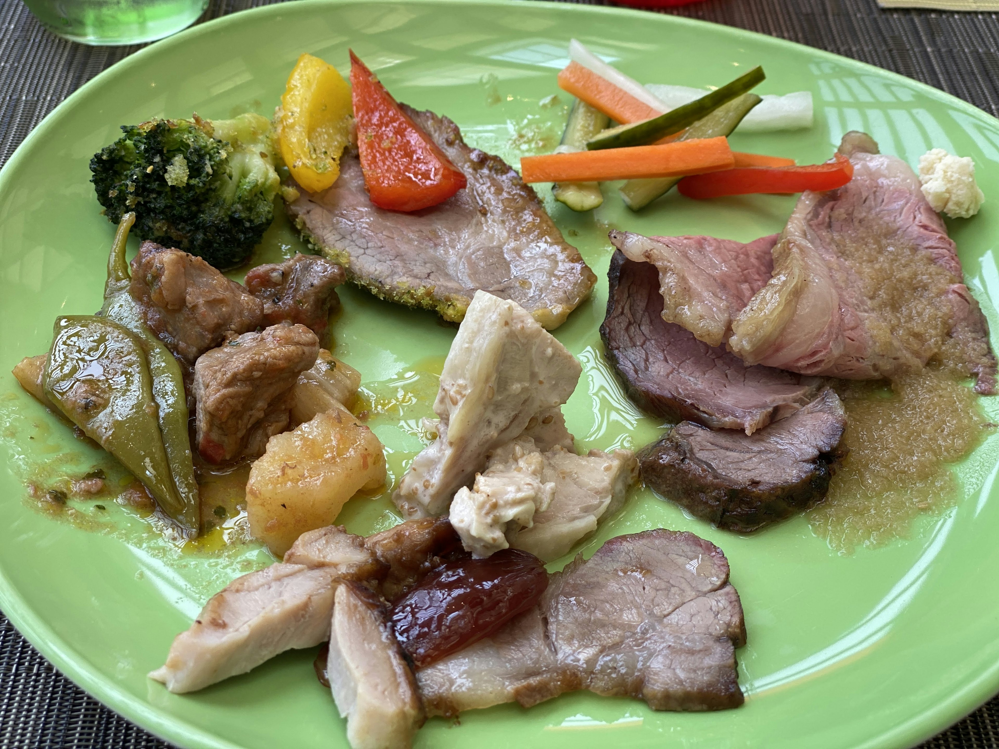 A variety of meat dishes and vegetables arranged on a green plate