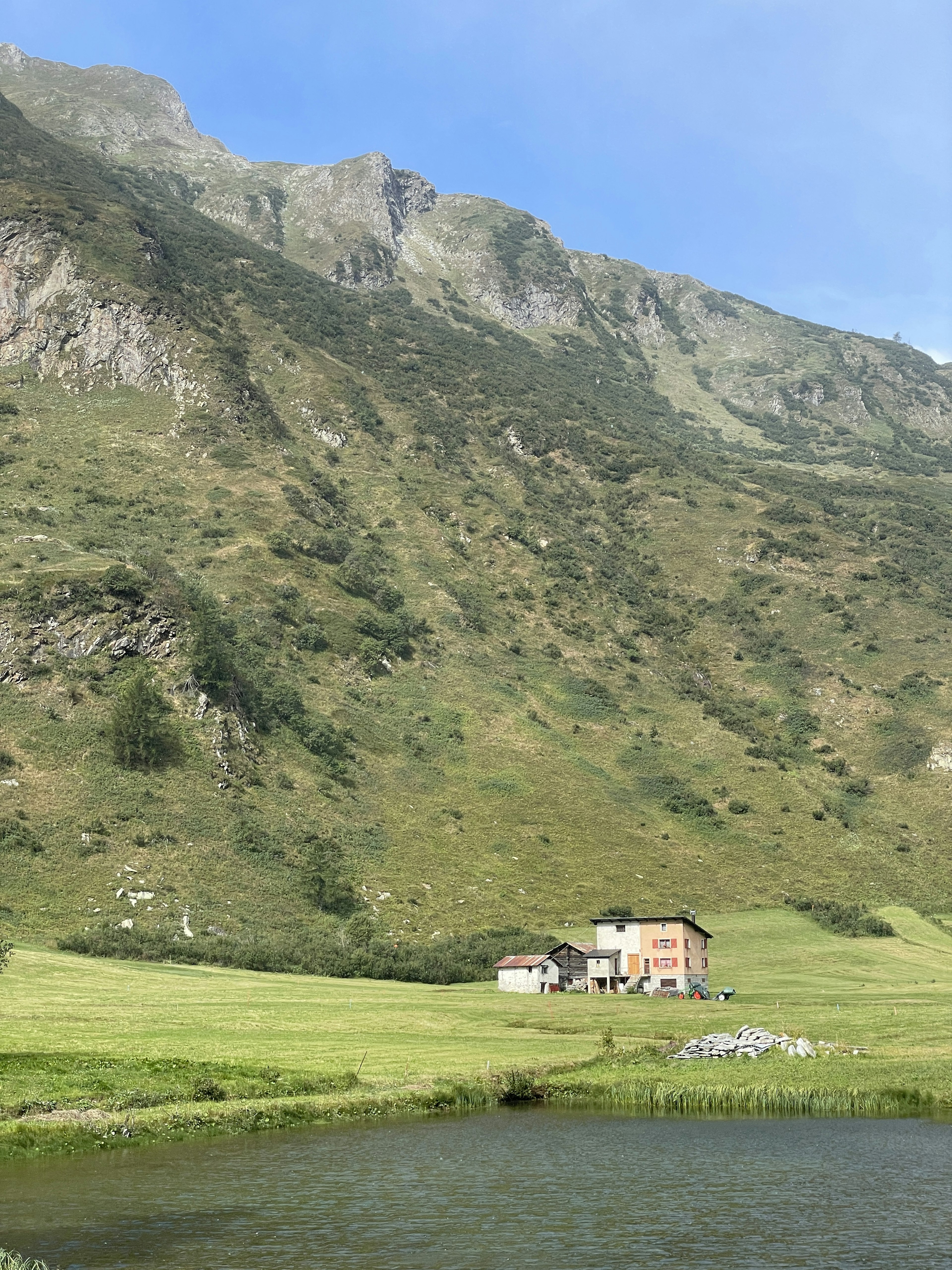 Ein Haus in einer grünen Wiese mit Bergen im Hintergrund