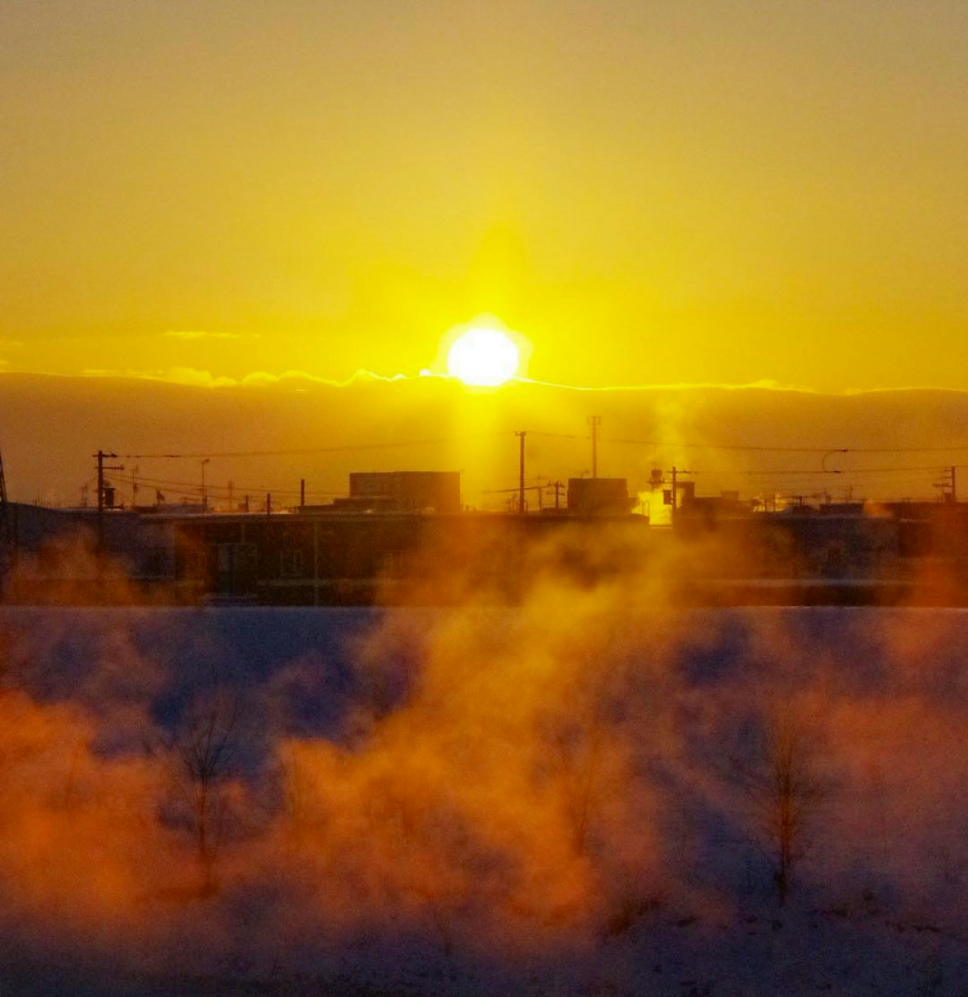 Winter landscape with a rising sun and misty smoke