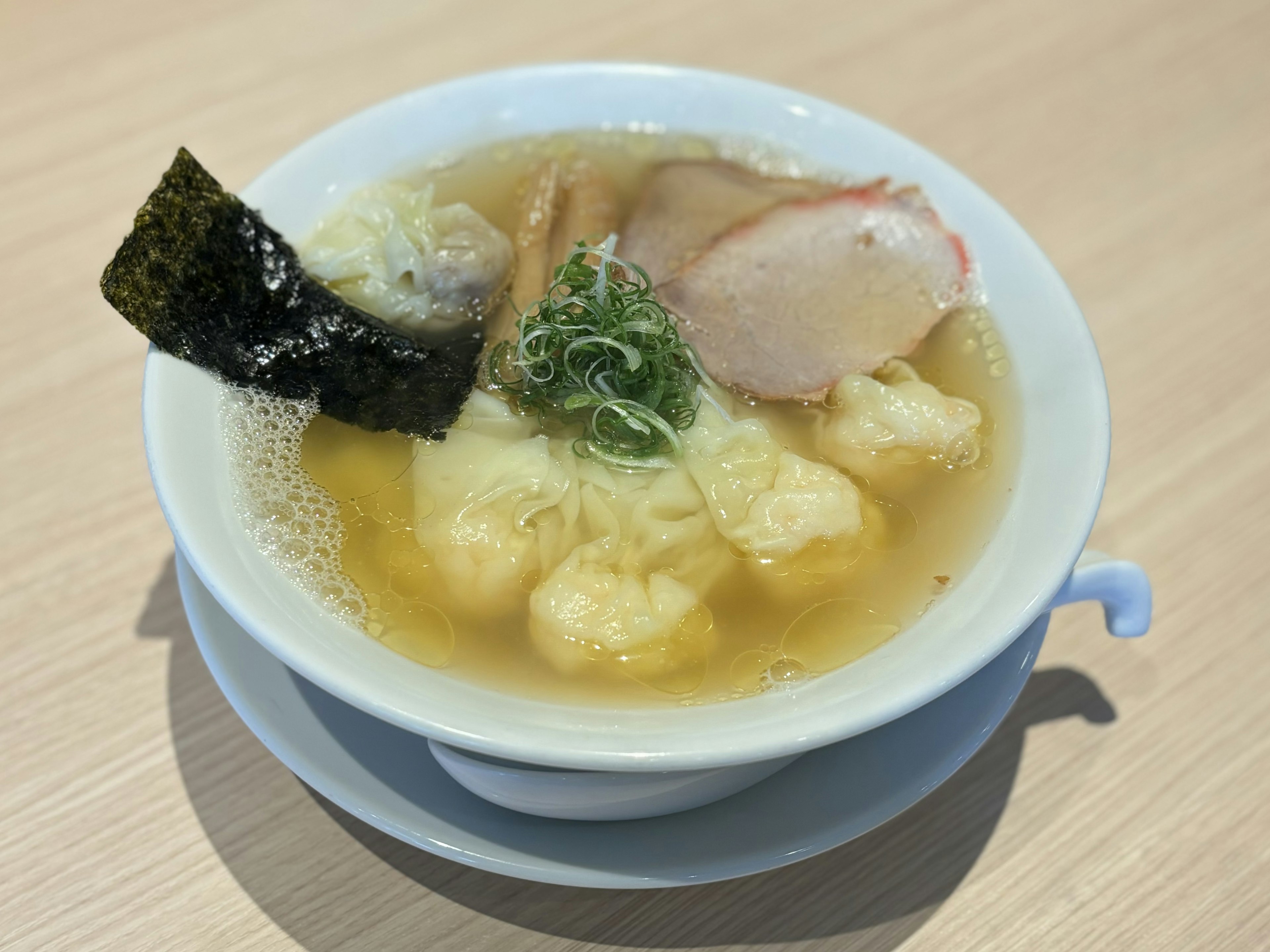 Ciotola di ramen in brodo chiaro con fette di maiale e alga nori