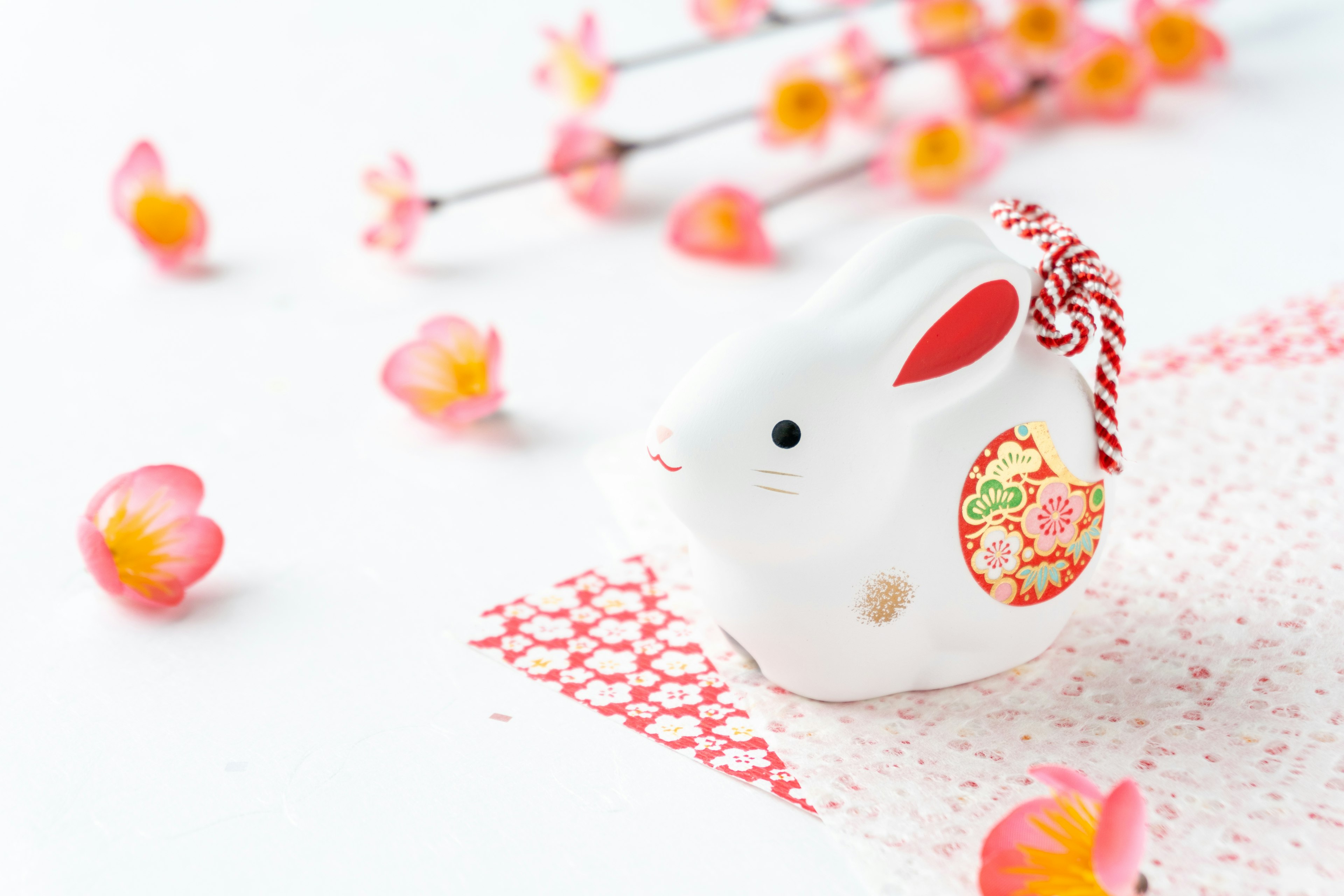 Figurine de lapin blanc avec des pétales de fleurs roses éparpillés