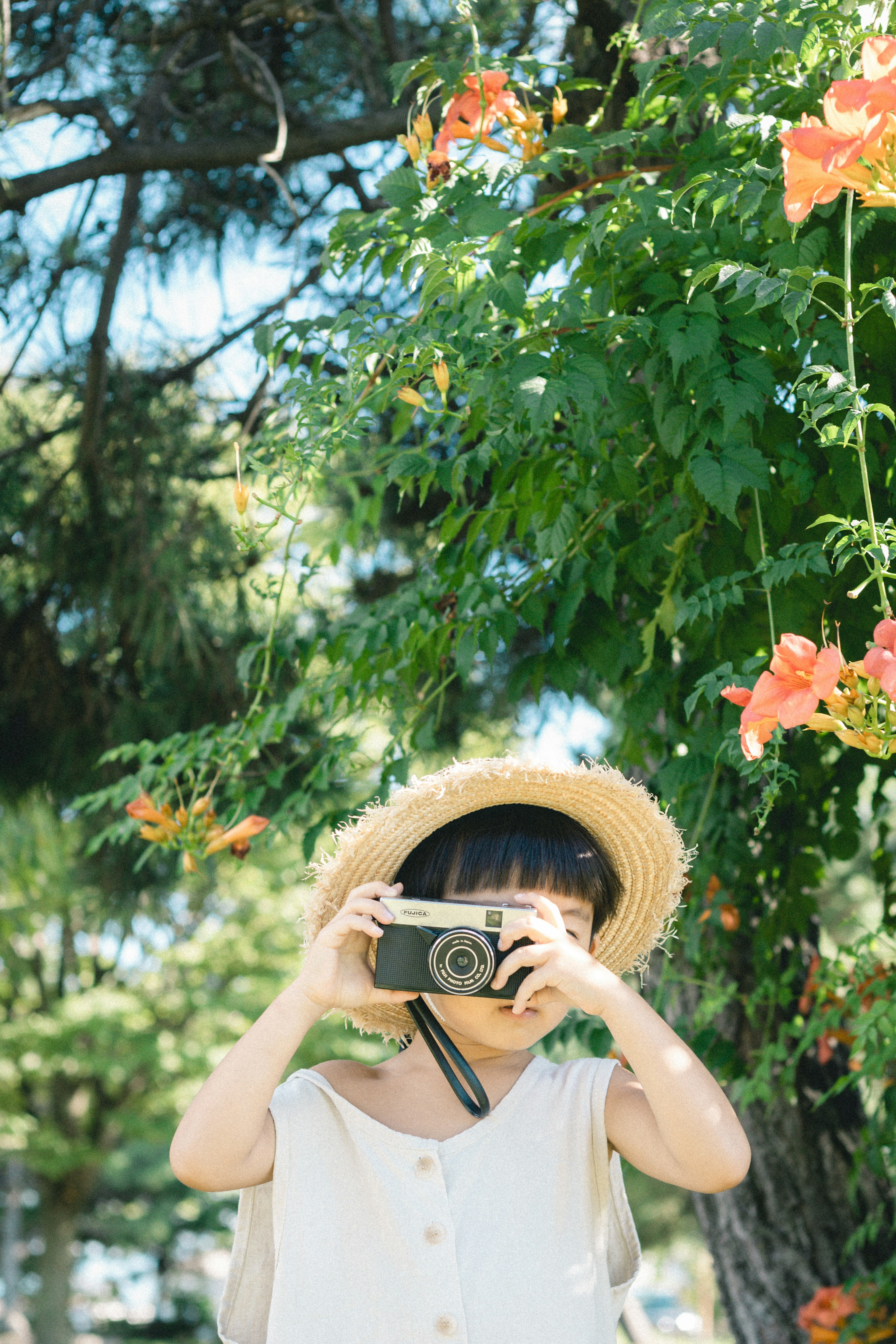 꽃 앞에서 카메라로 사진을 찍는 여성