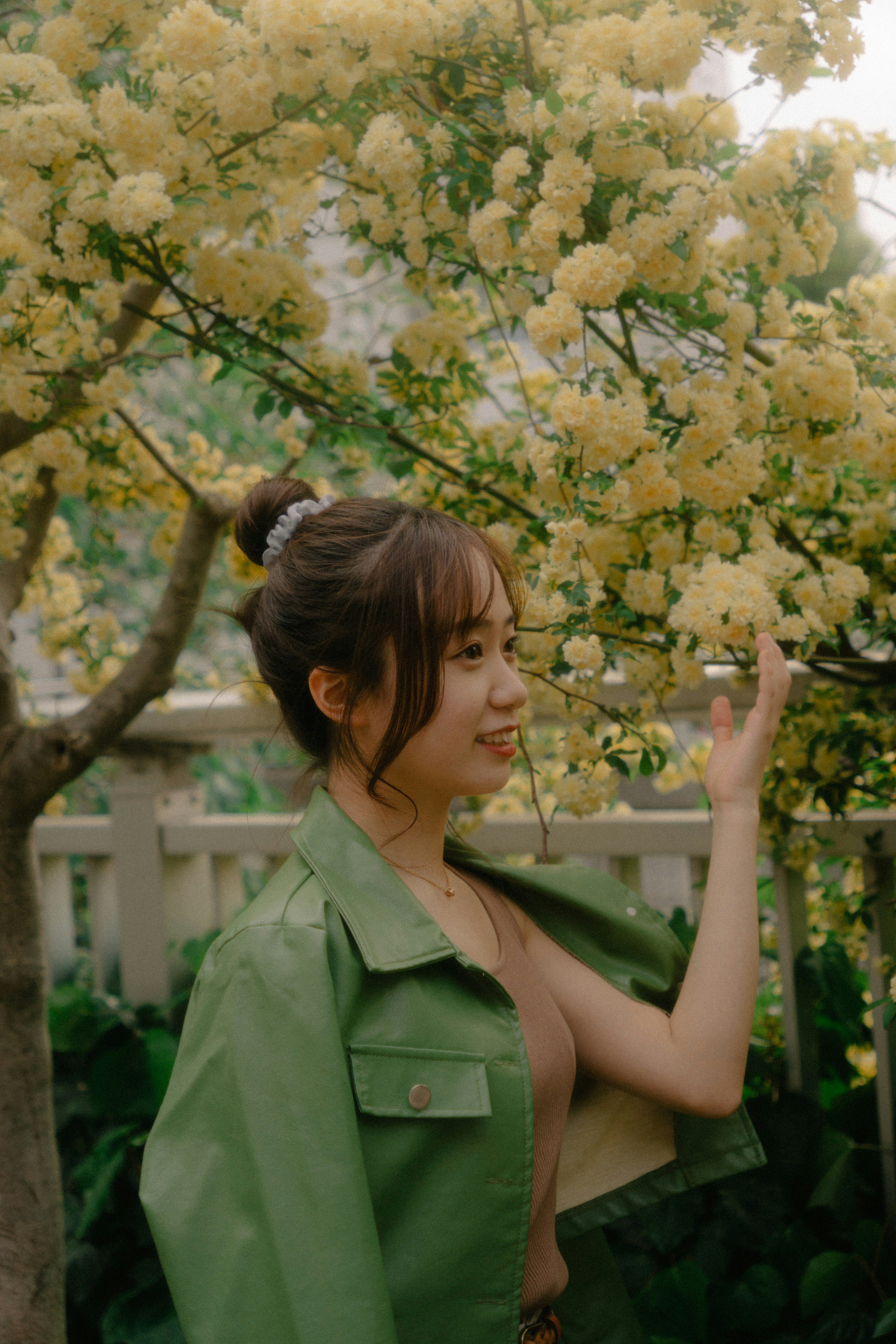 Mujer sonriendo frente a un árbol con flores amarillas