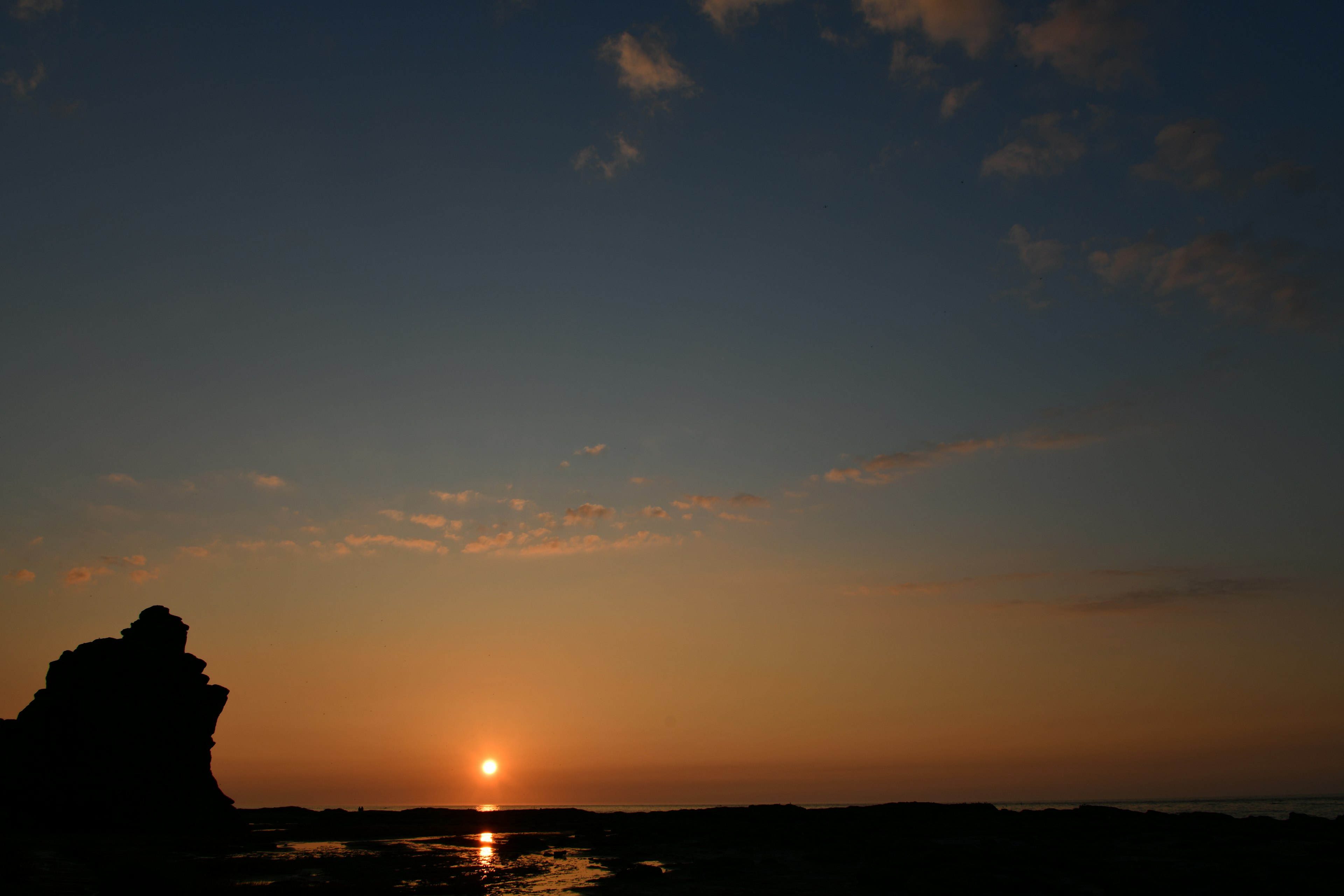 海岸線で夕日が沈む風景と岩