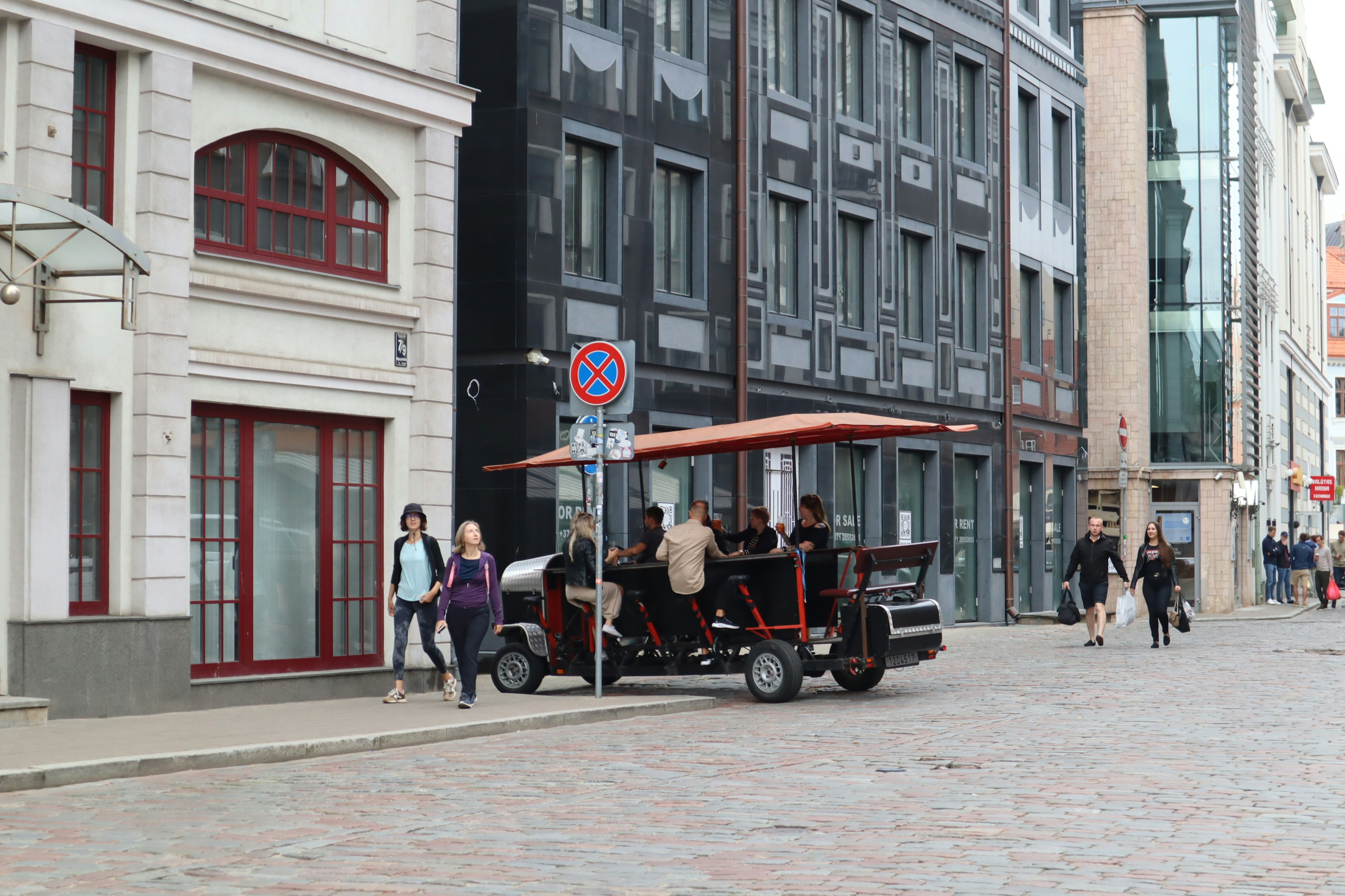 A street scene featuring an old vehicle and pedestrians