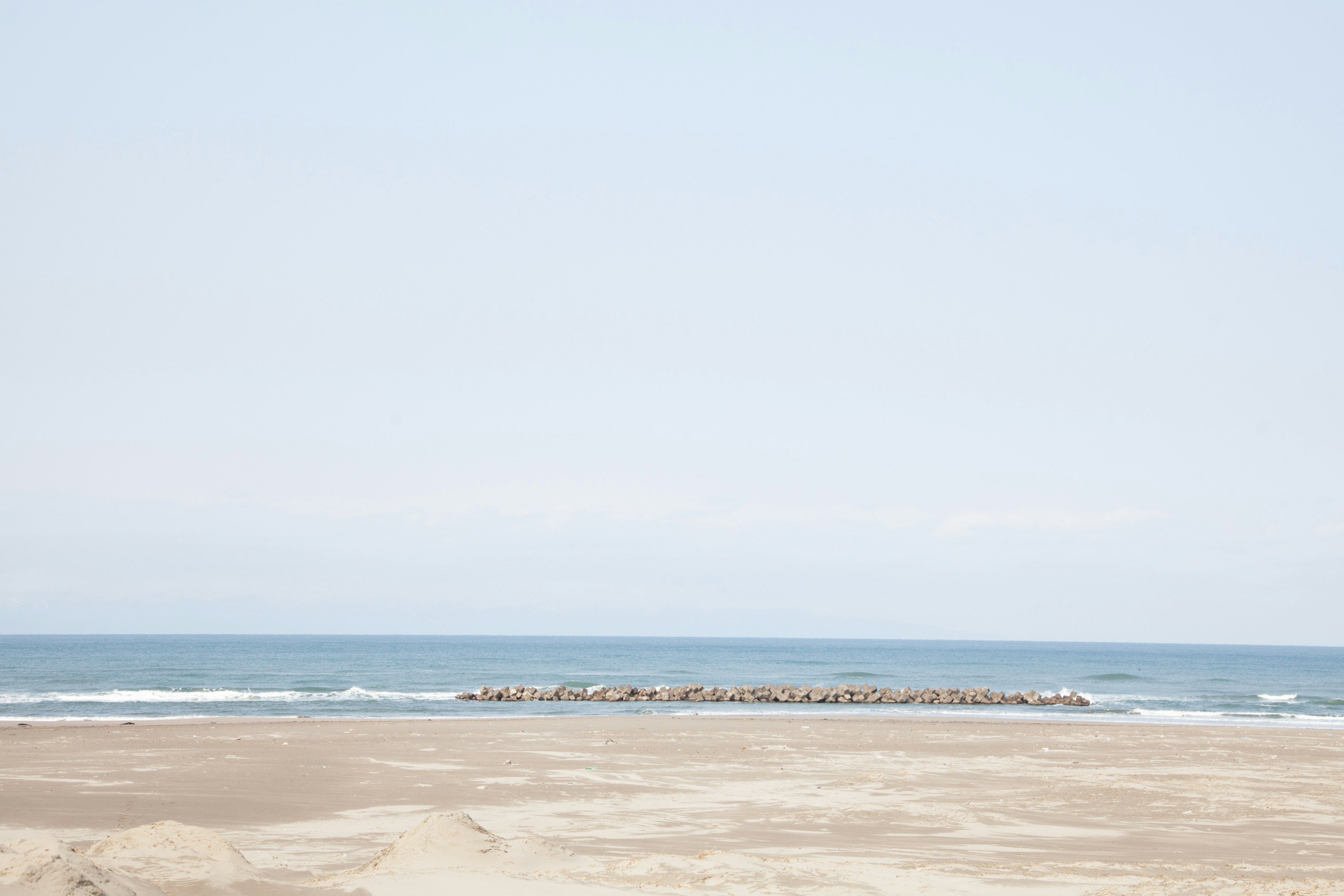 Calm sea and blue sky scene with beach and rock formation