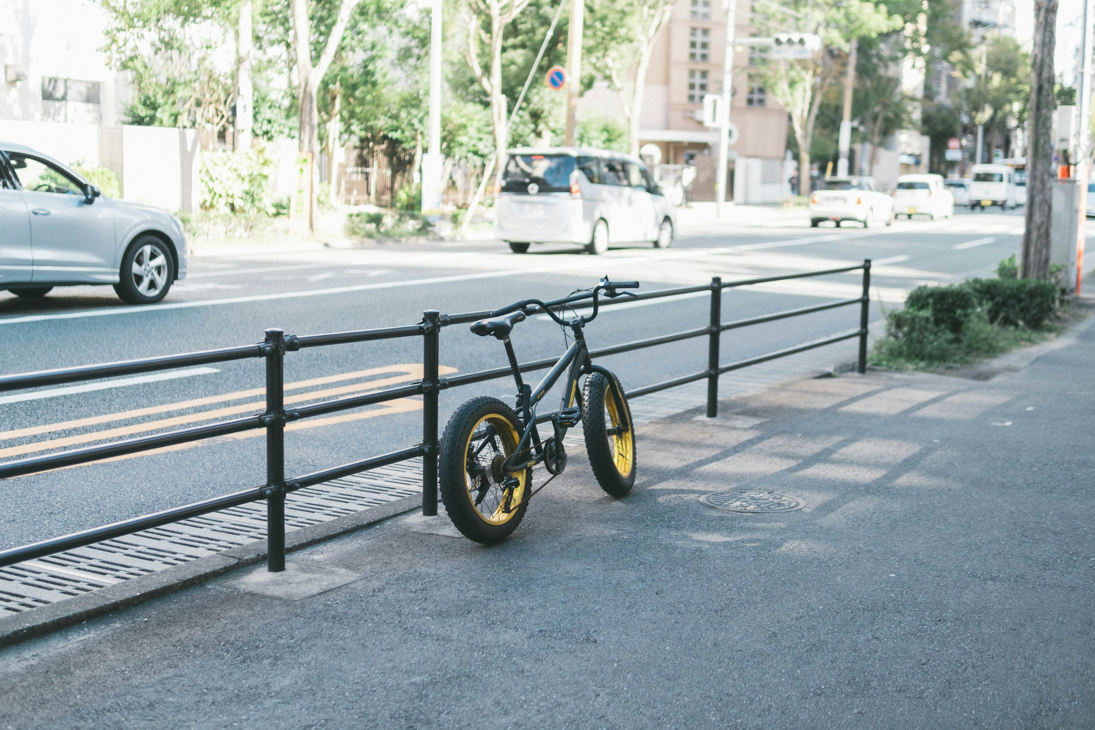 黒い自転車が黄色いホイールで街路に停まっている