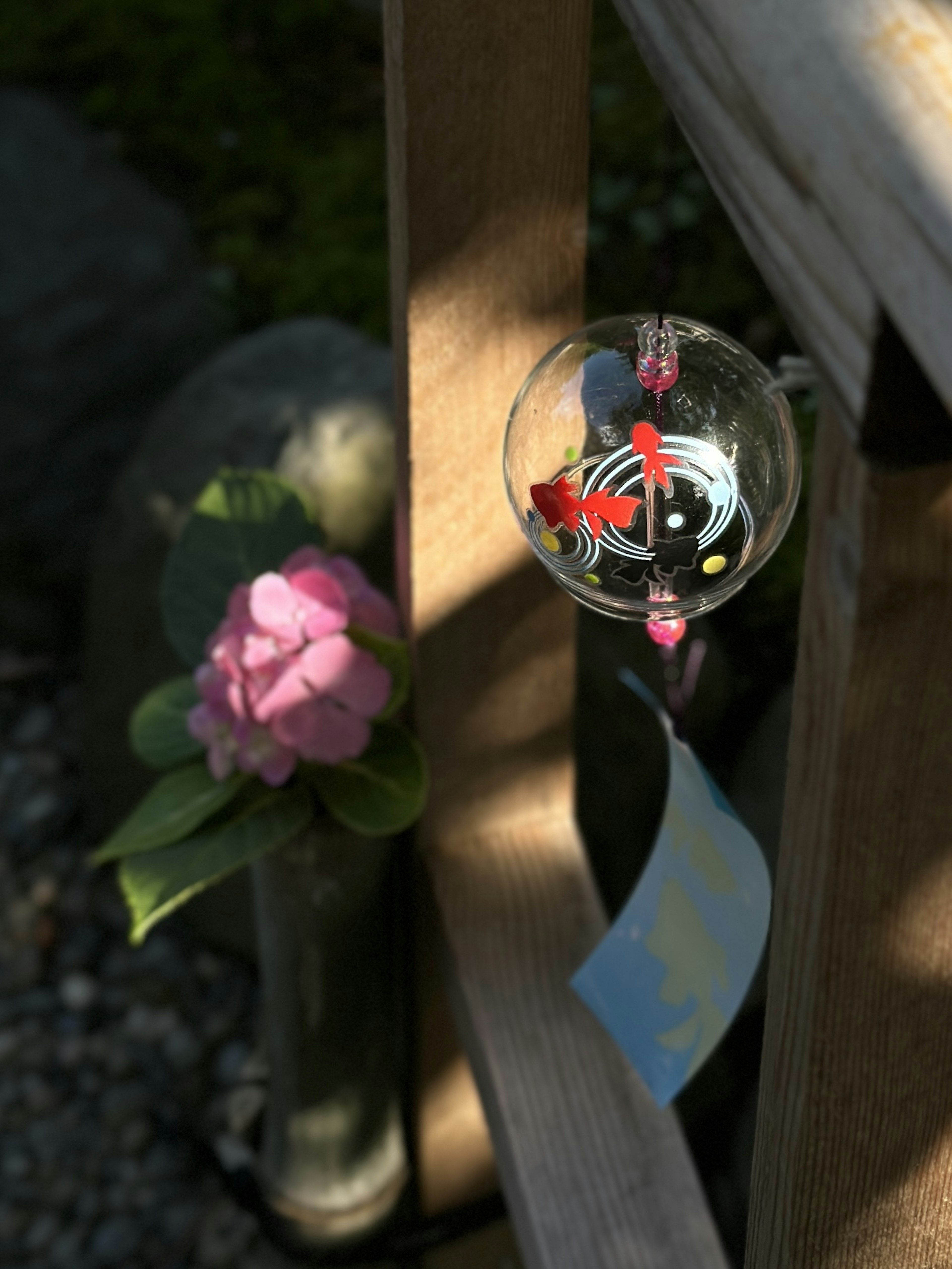 Wind chime and pink flower on a wooden fence