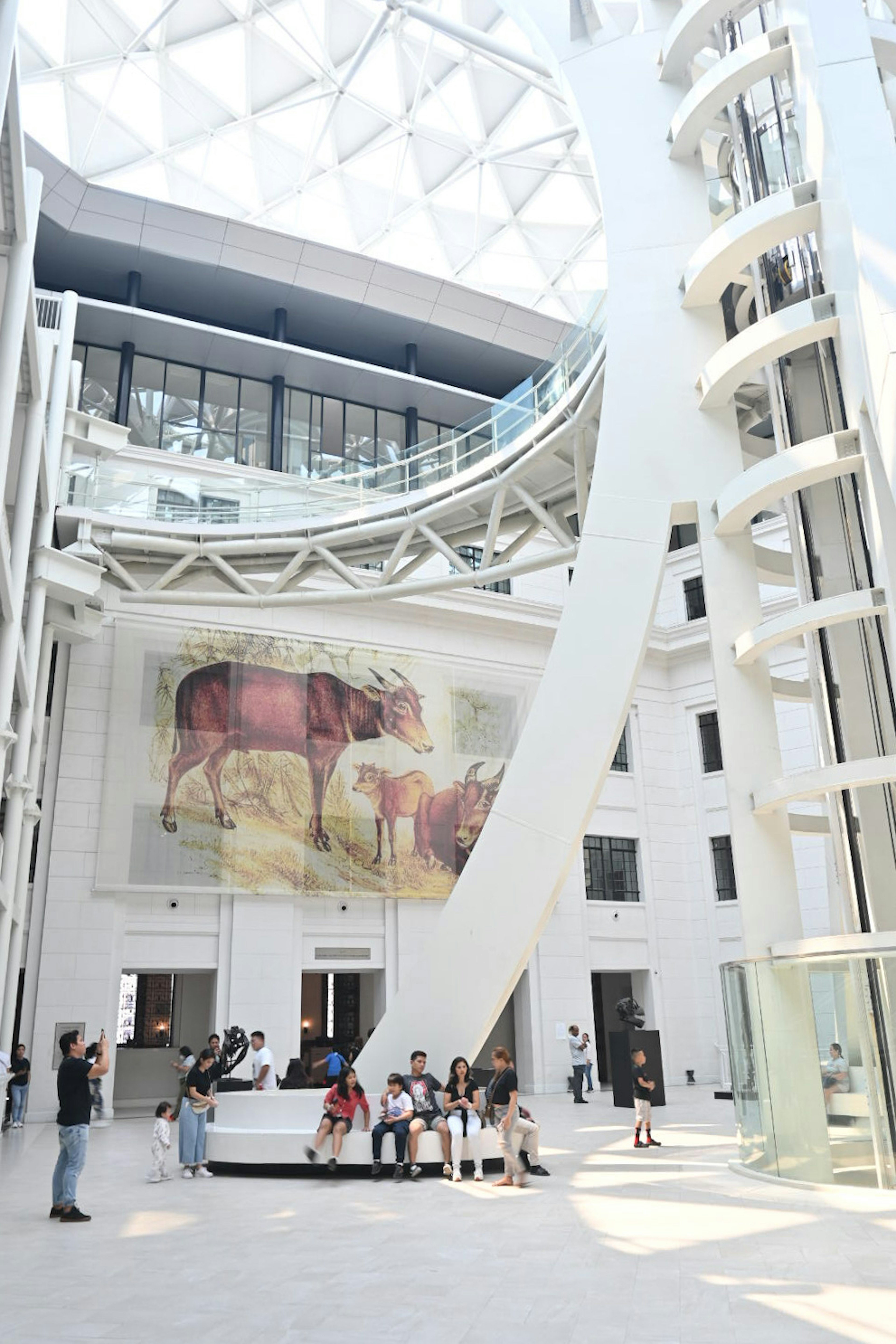 Interior of a modern building featuring a large art piece and people gathering