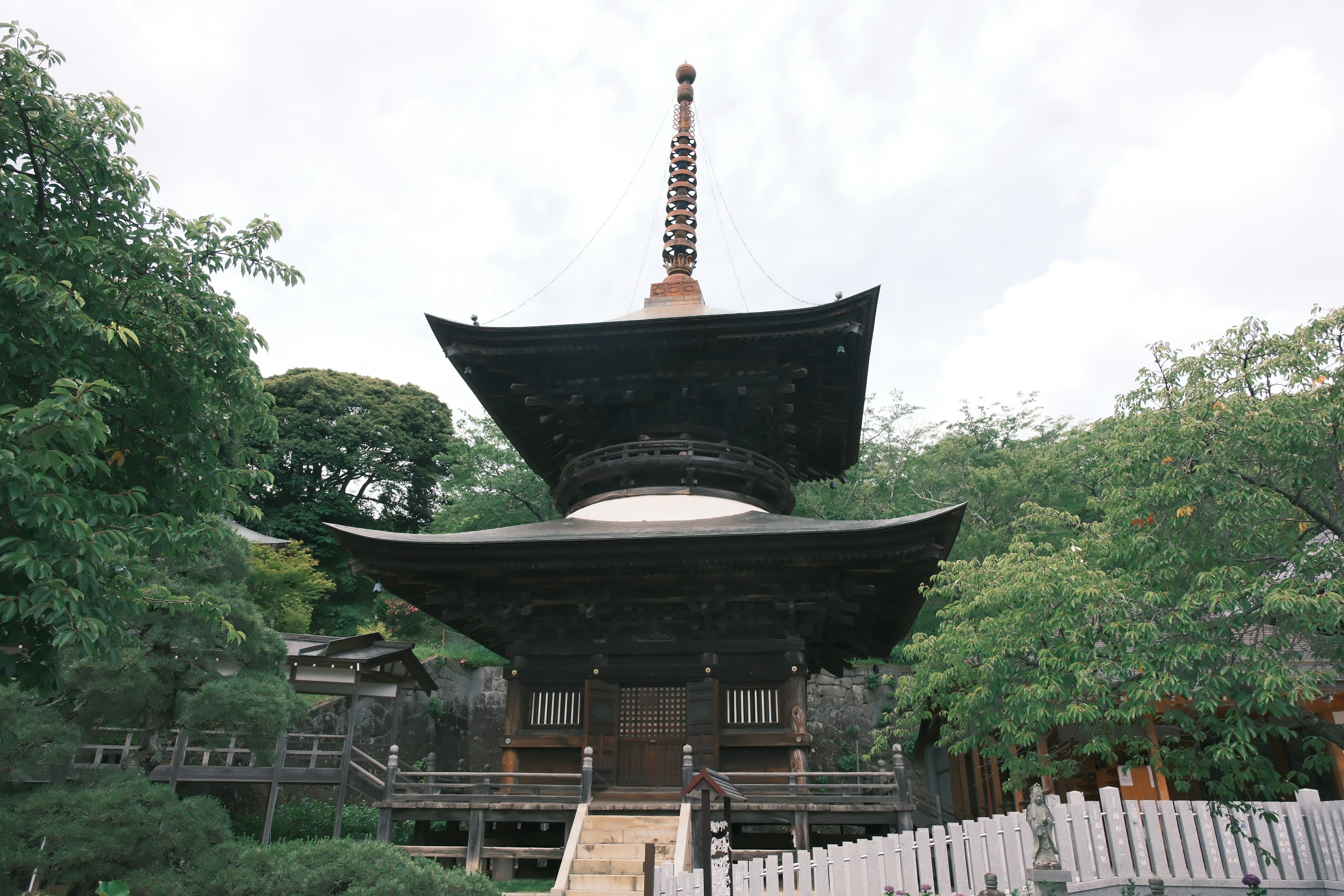 Traditioneller japanischer Tempel mit schwarzem Dach umgeben von grünen Bäumen