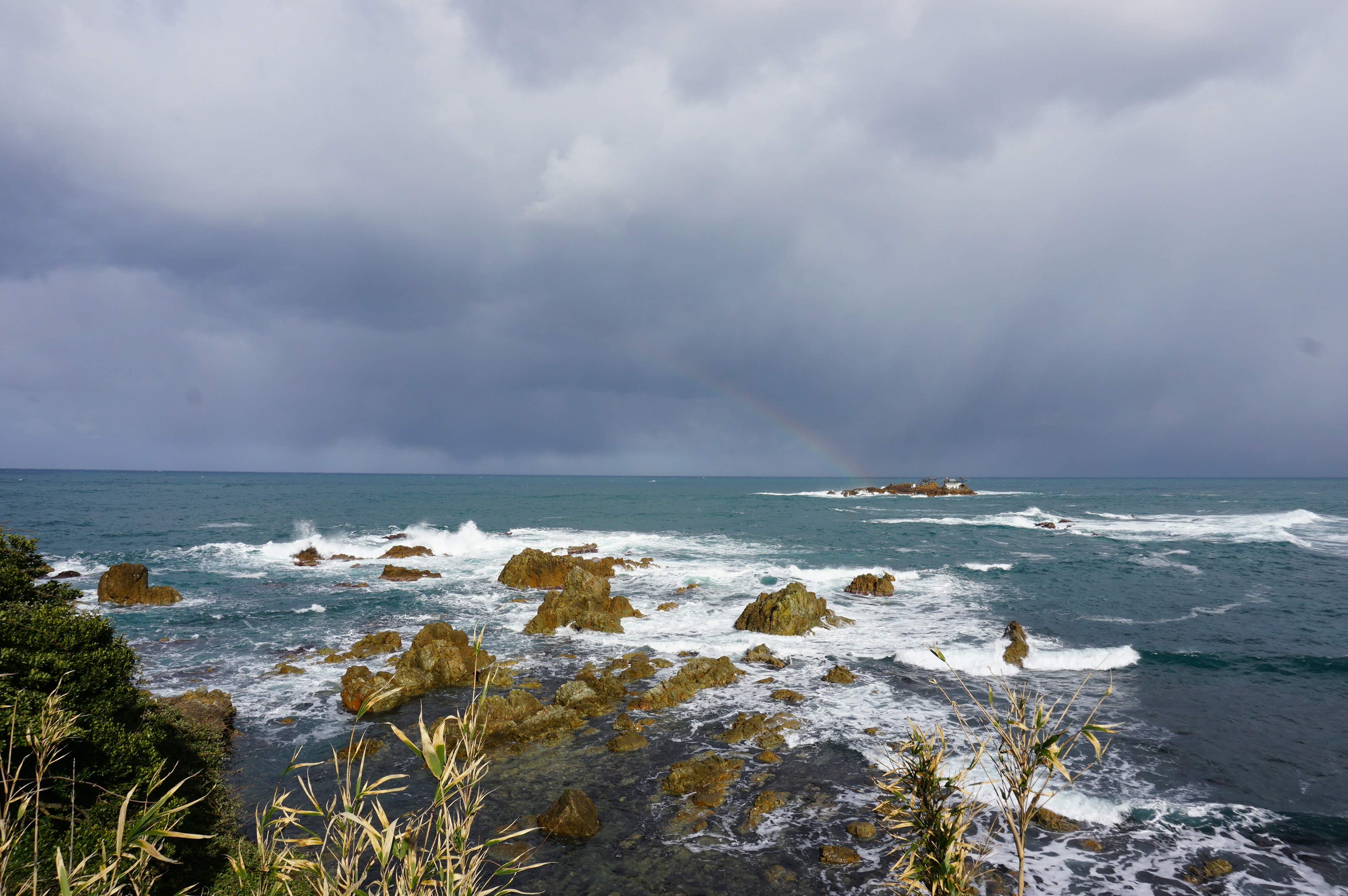 Costa escarpada con formaciones rocosas bajo un cielo nublado y olas rompiendo