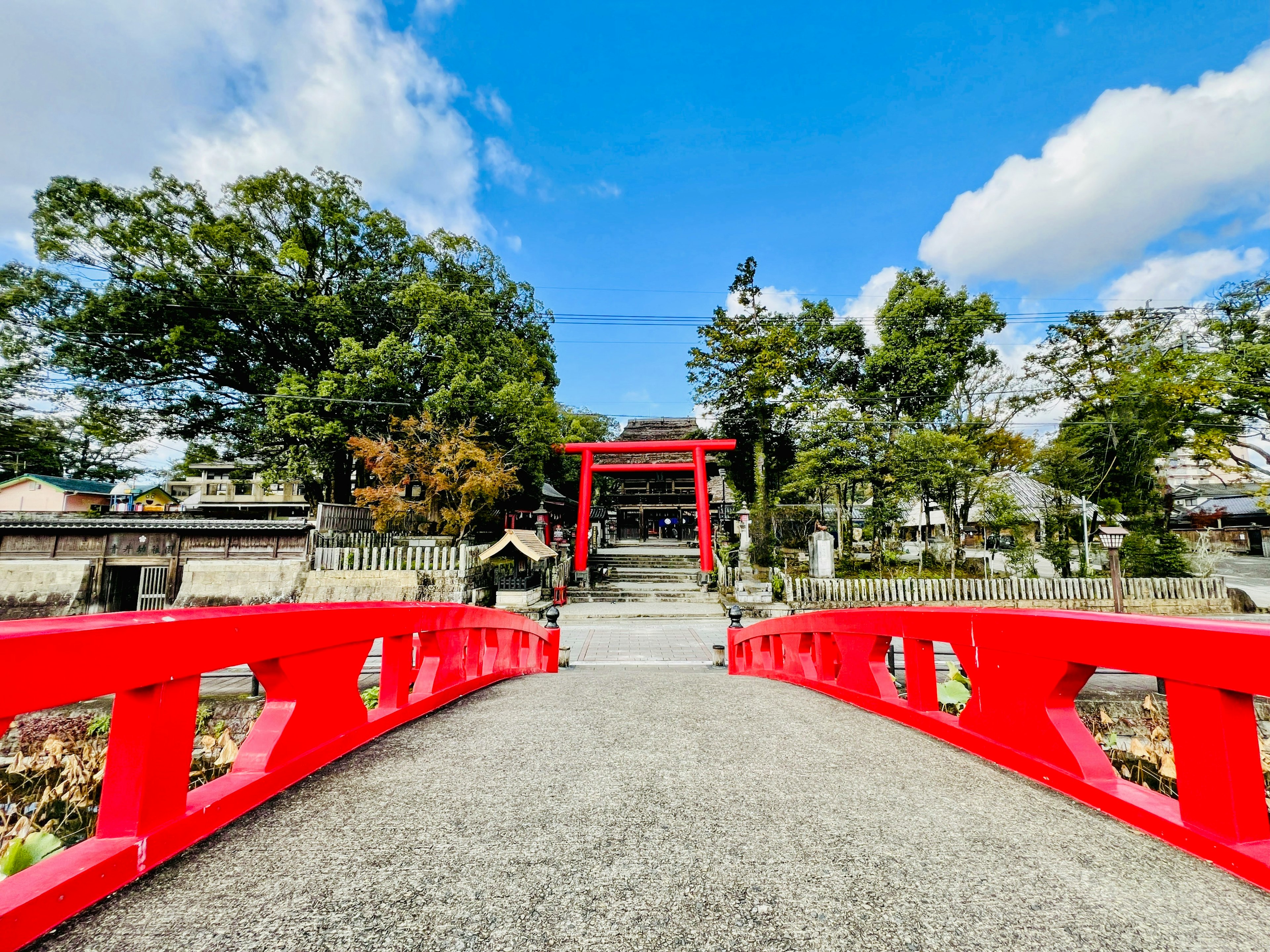 赤い橋と神社の入り口が見える風景