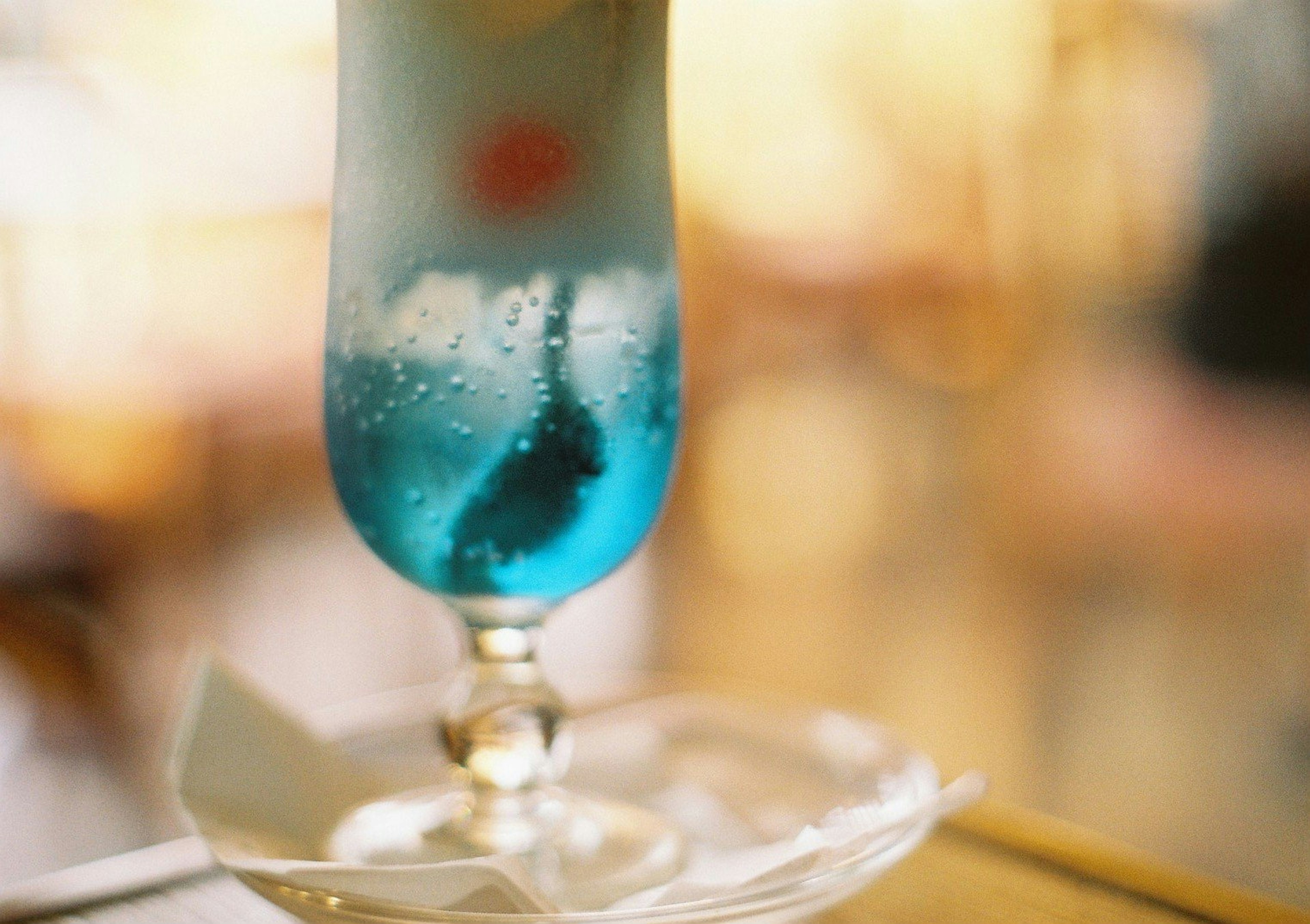 A blue cocktail served in a glass on a table