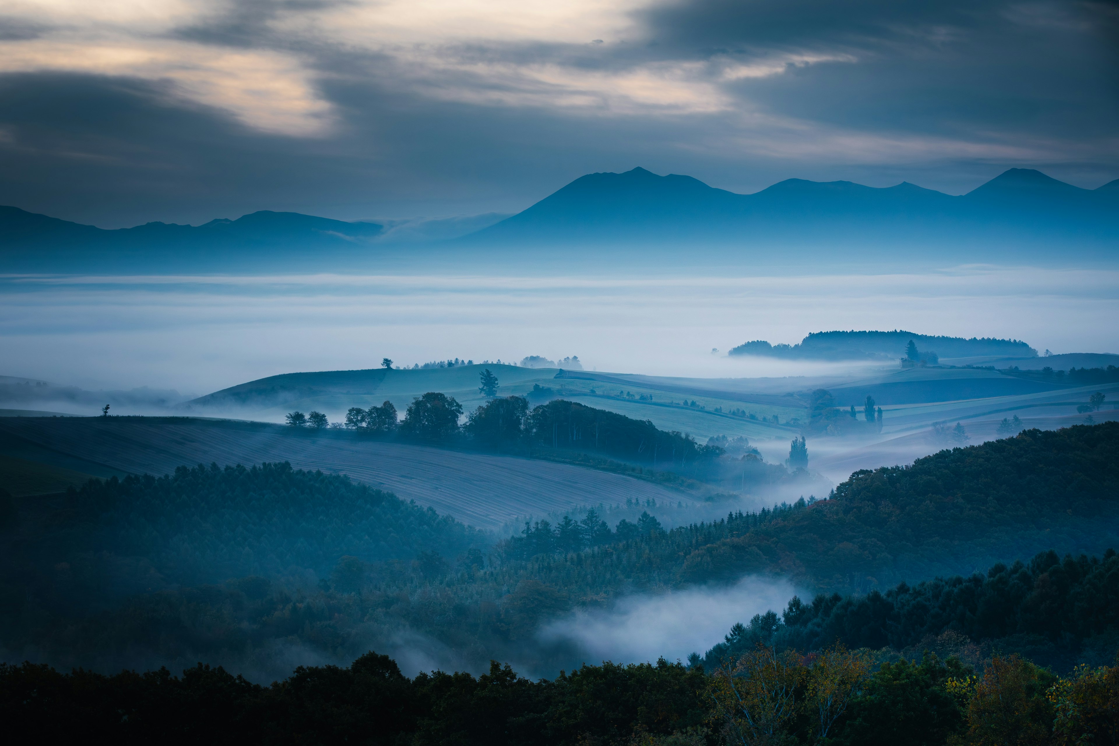 Eine Landschaft von Bergen und Tälern, umhüllt von blauer Nebel