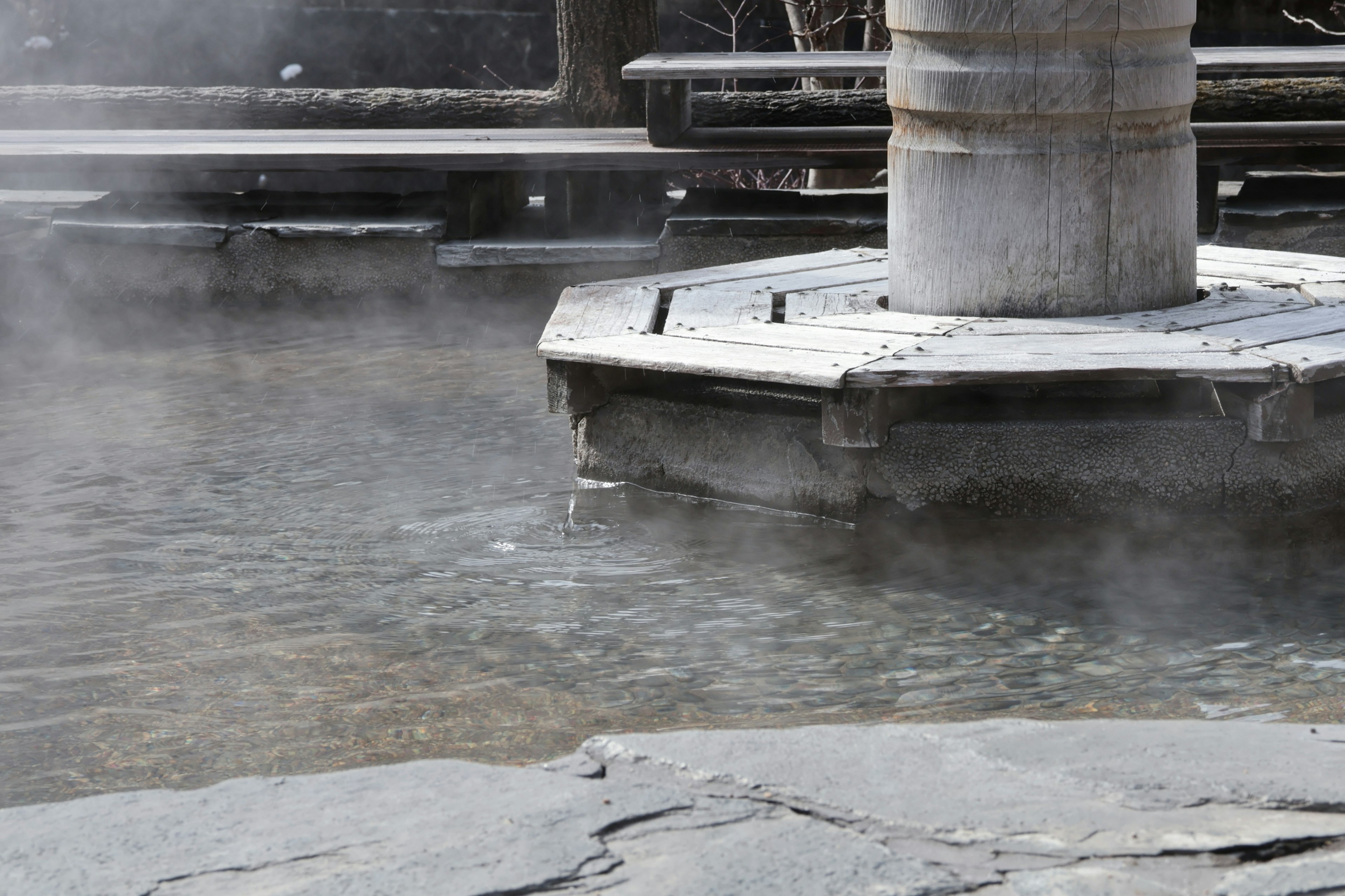 Steam rising from a stone platform in a hot spring