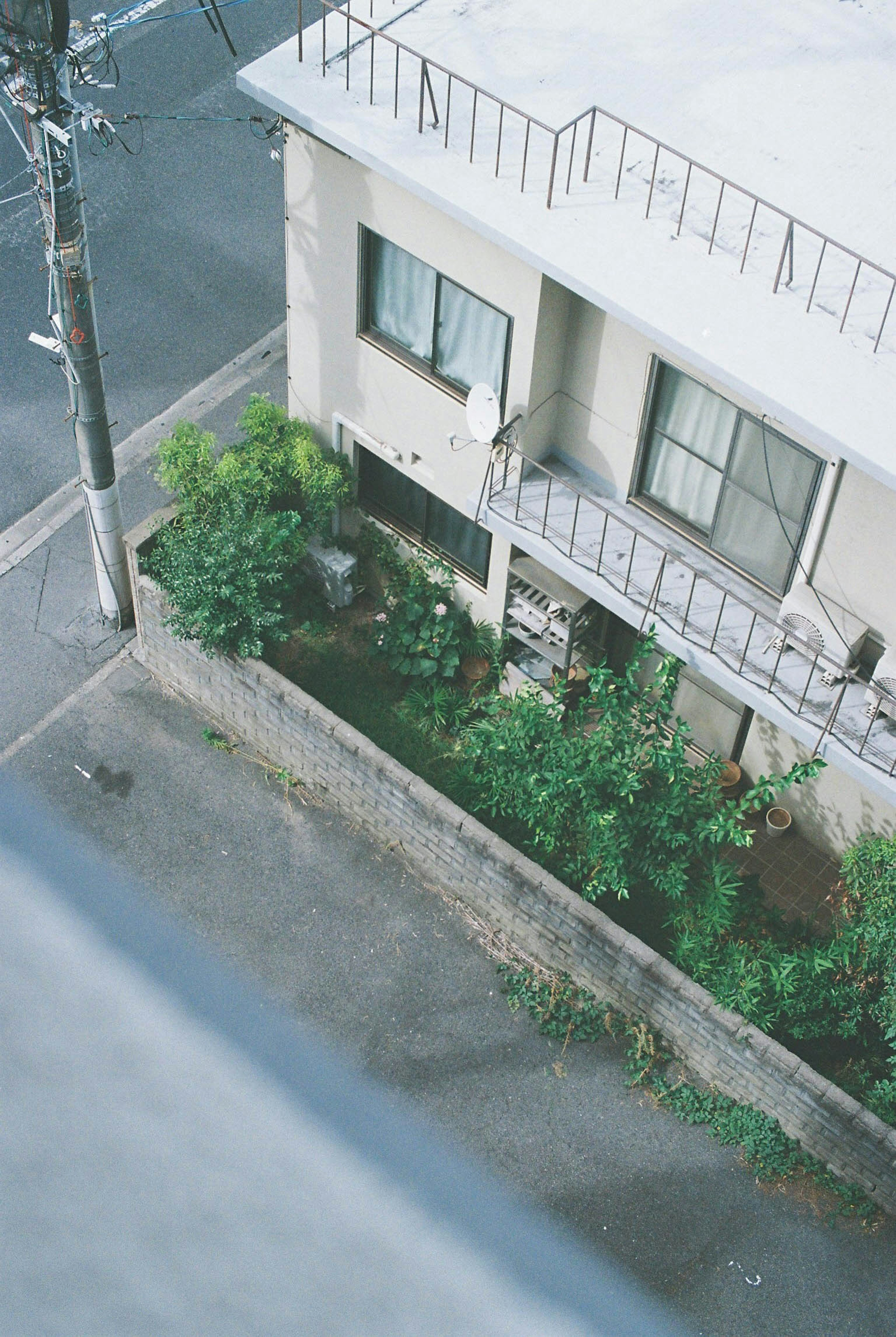 A view of a house's garden and surrounding street from a high angle