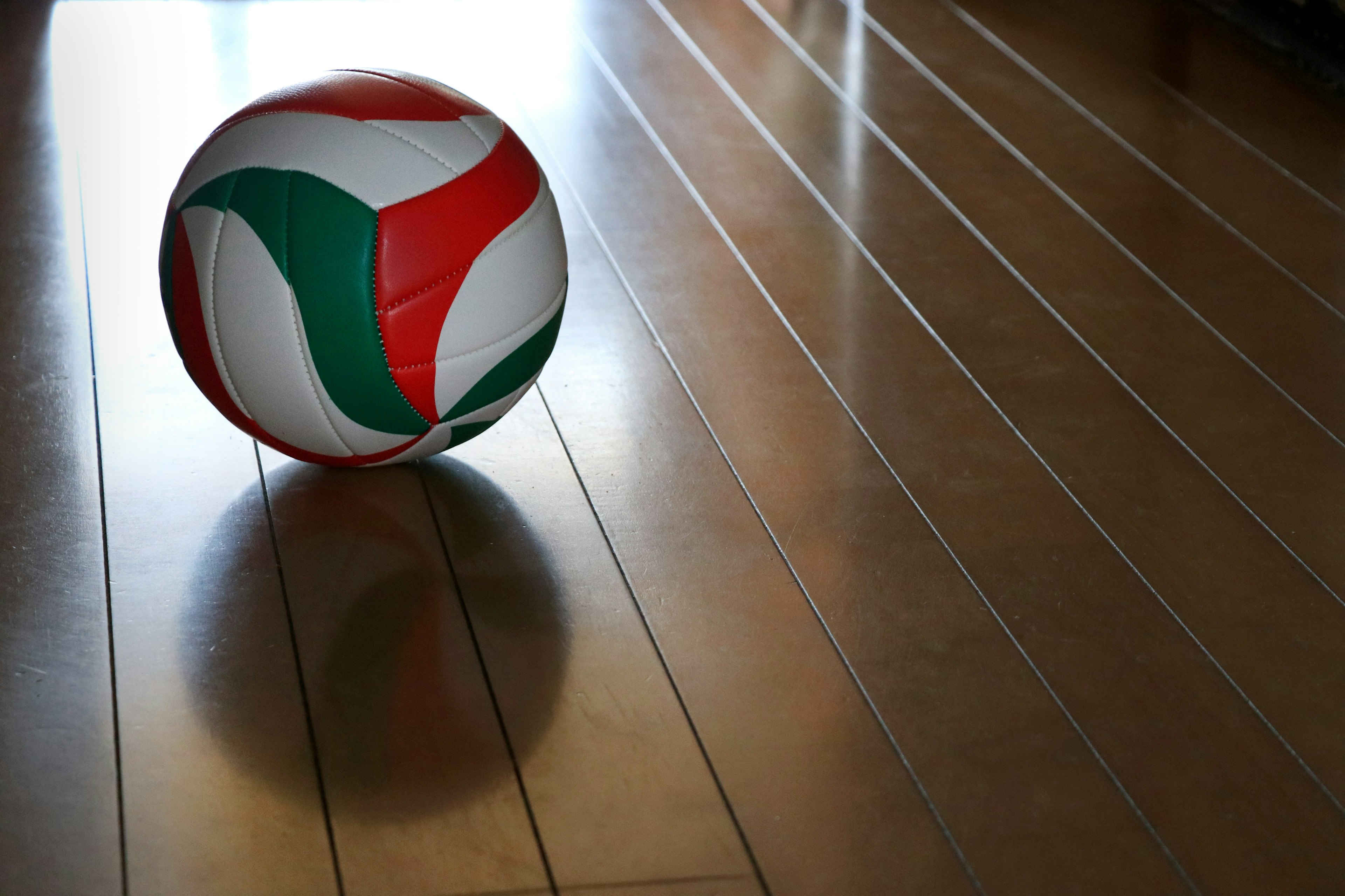 A red and green patterned ball on a wooden floor