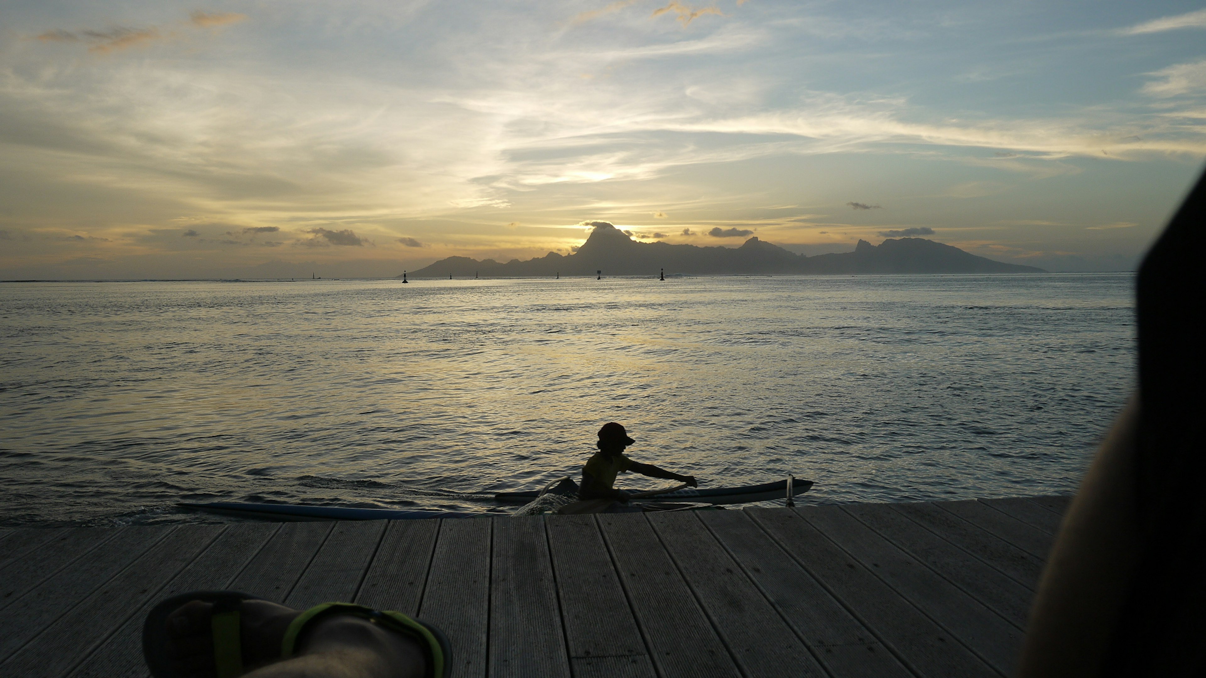 Persona en kayak al atardecer con montañas al fondo