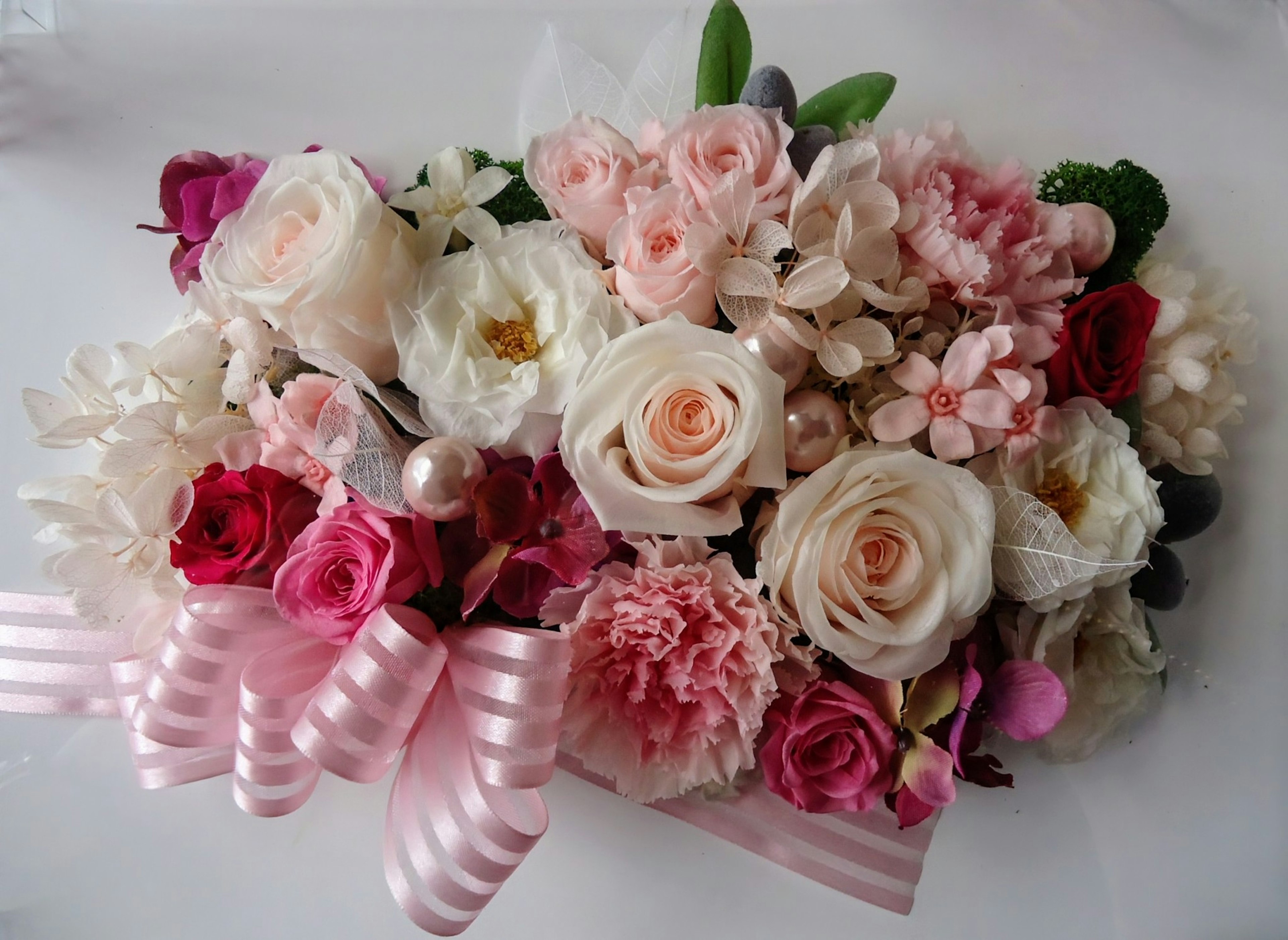 A beautiful floral arrangement featuring a variety of colorful flowers with pink ribbons