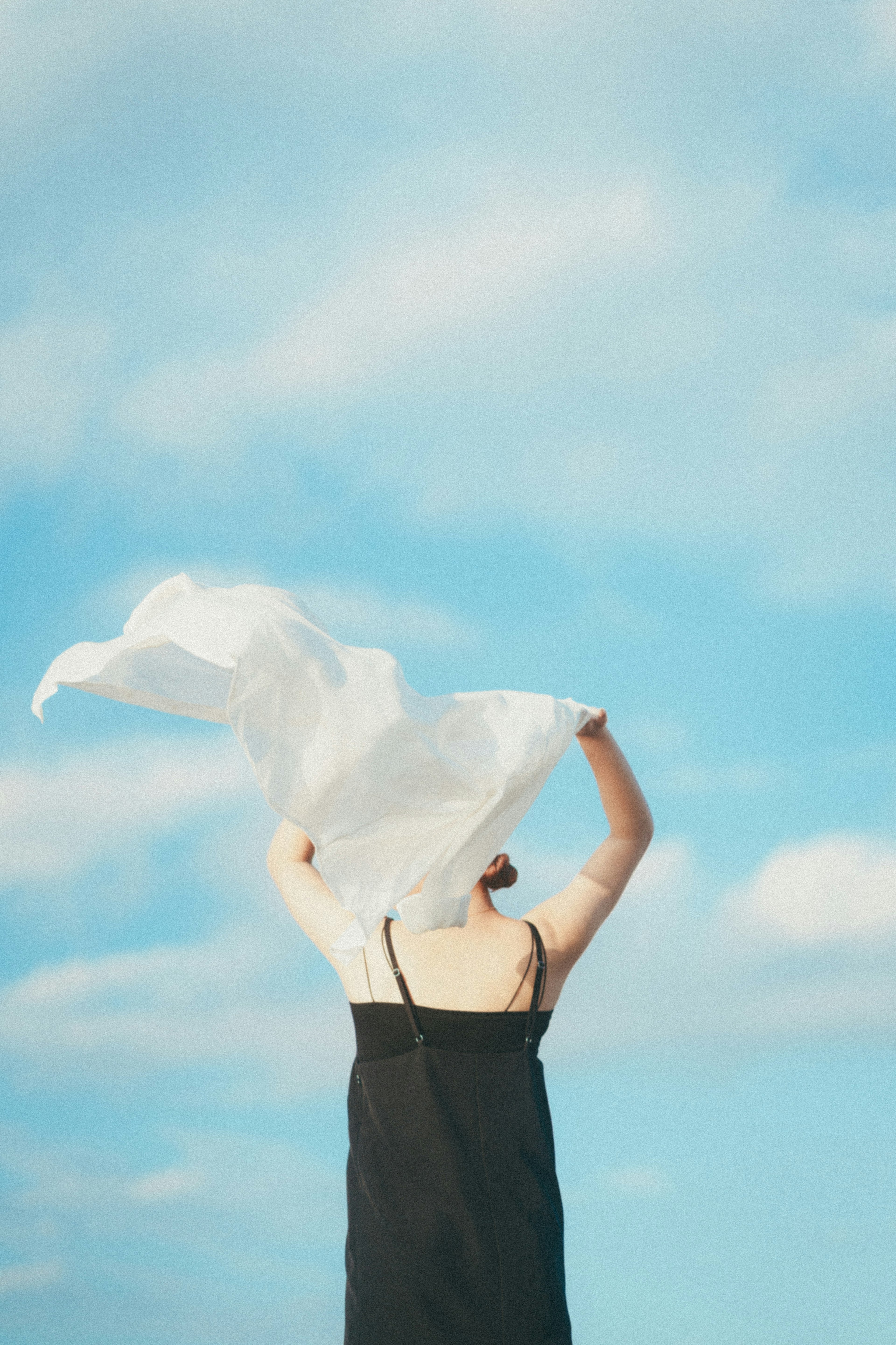 Woman holding a white cloth against a blue sky