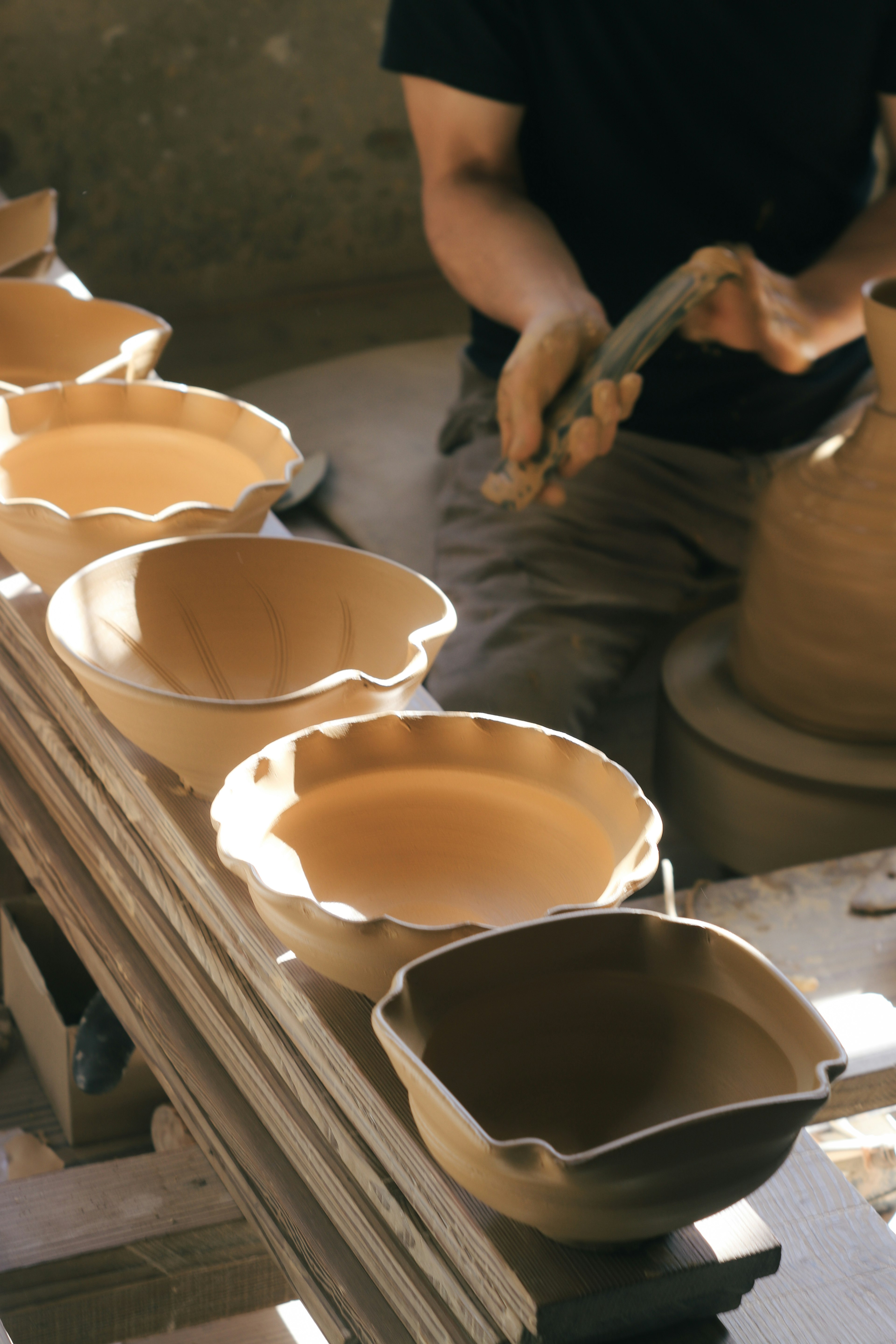 Un potier façonnant des bols en argile et une vase avec de la poterie en cours