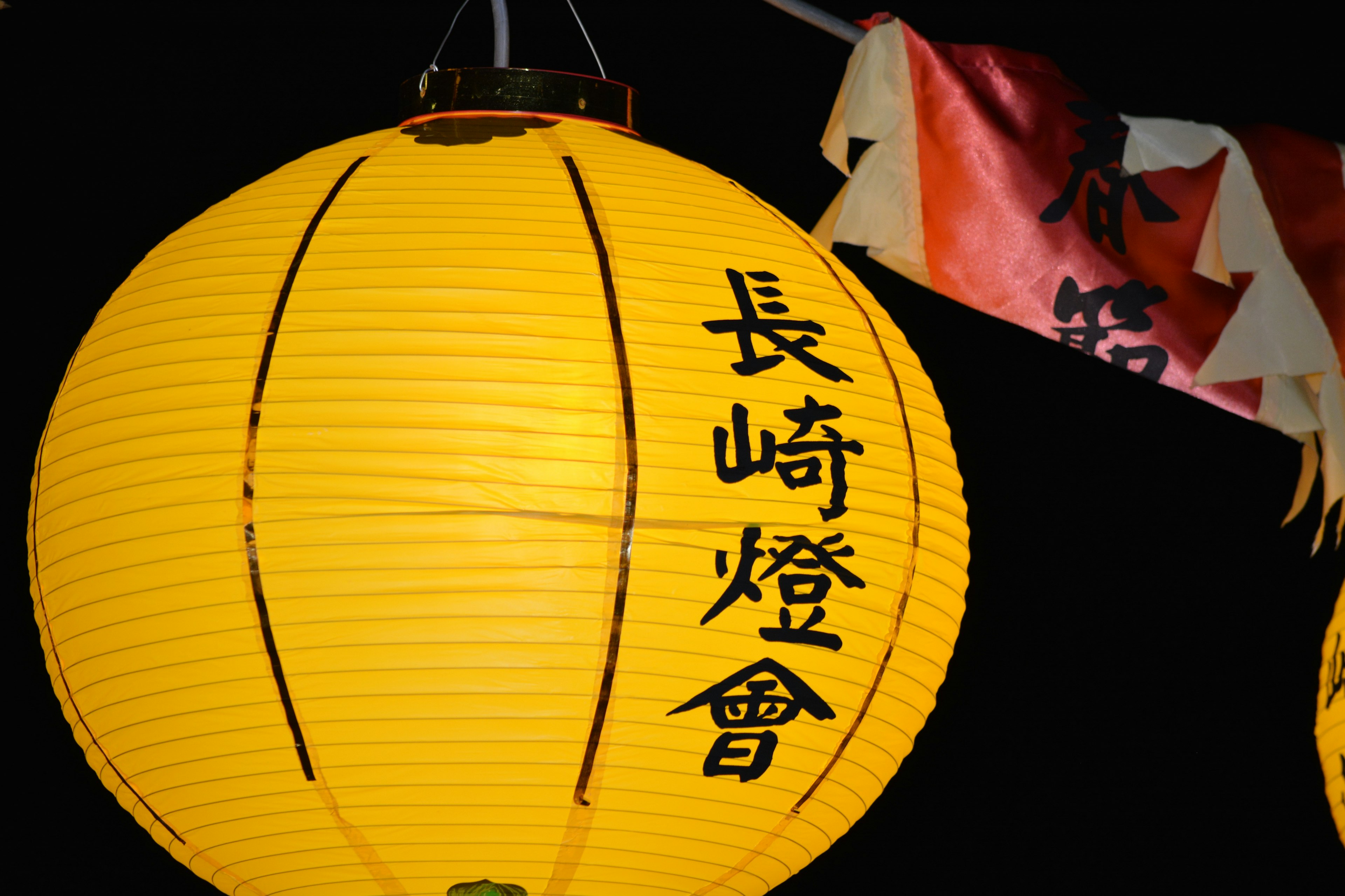 Lanternes jaunes avec des caractères de l'Association des lanternes de Nagasaki dans une scène nocturne