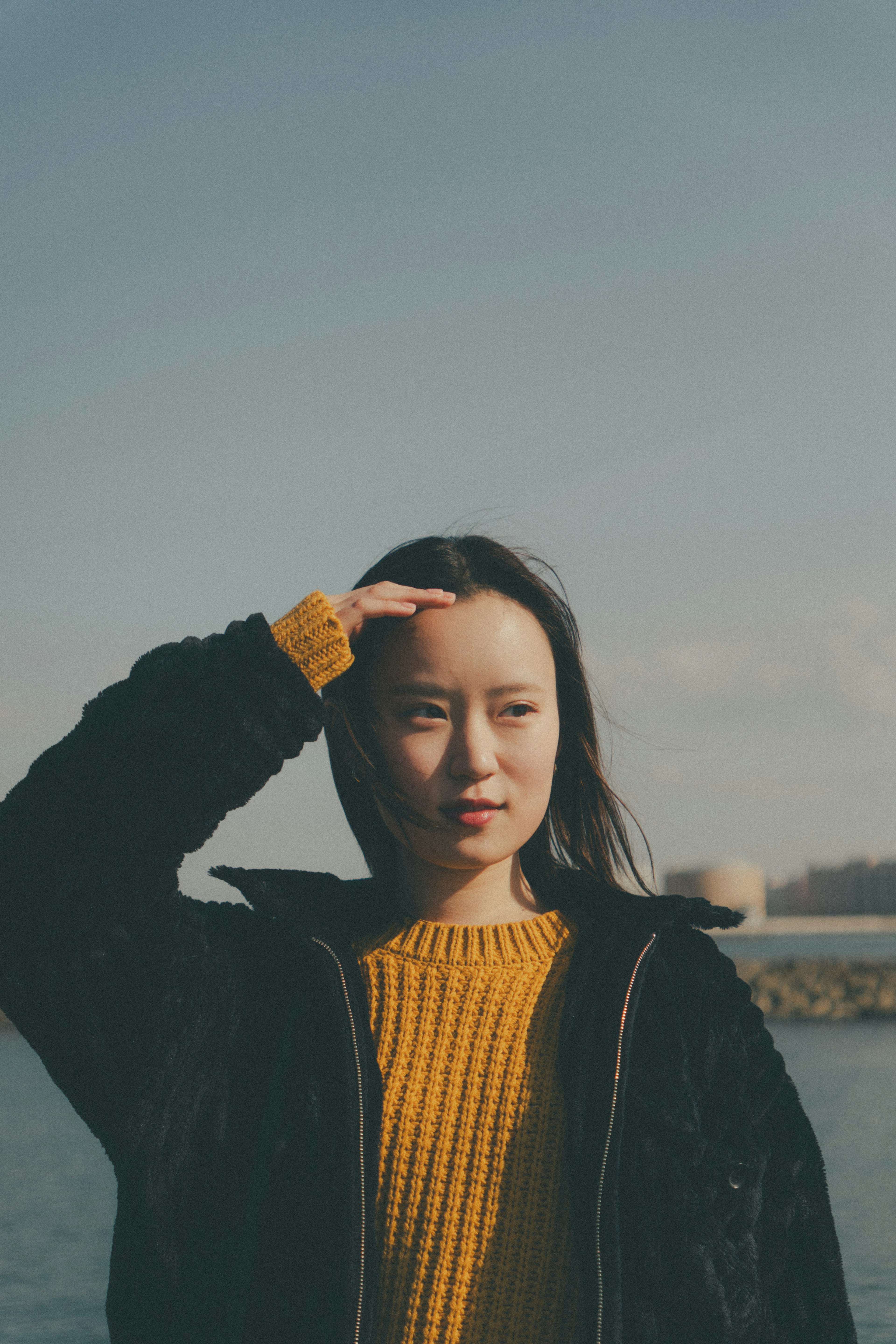 海辺で手をかざしている女性が写っている晴れた日の風景