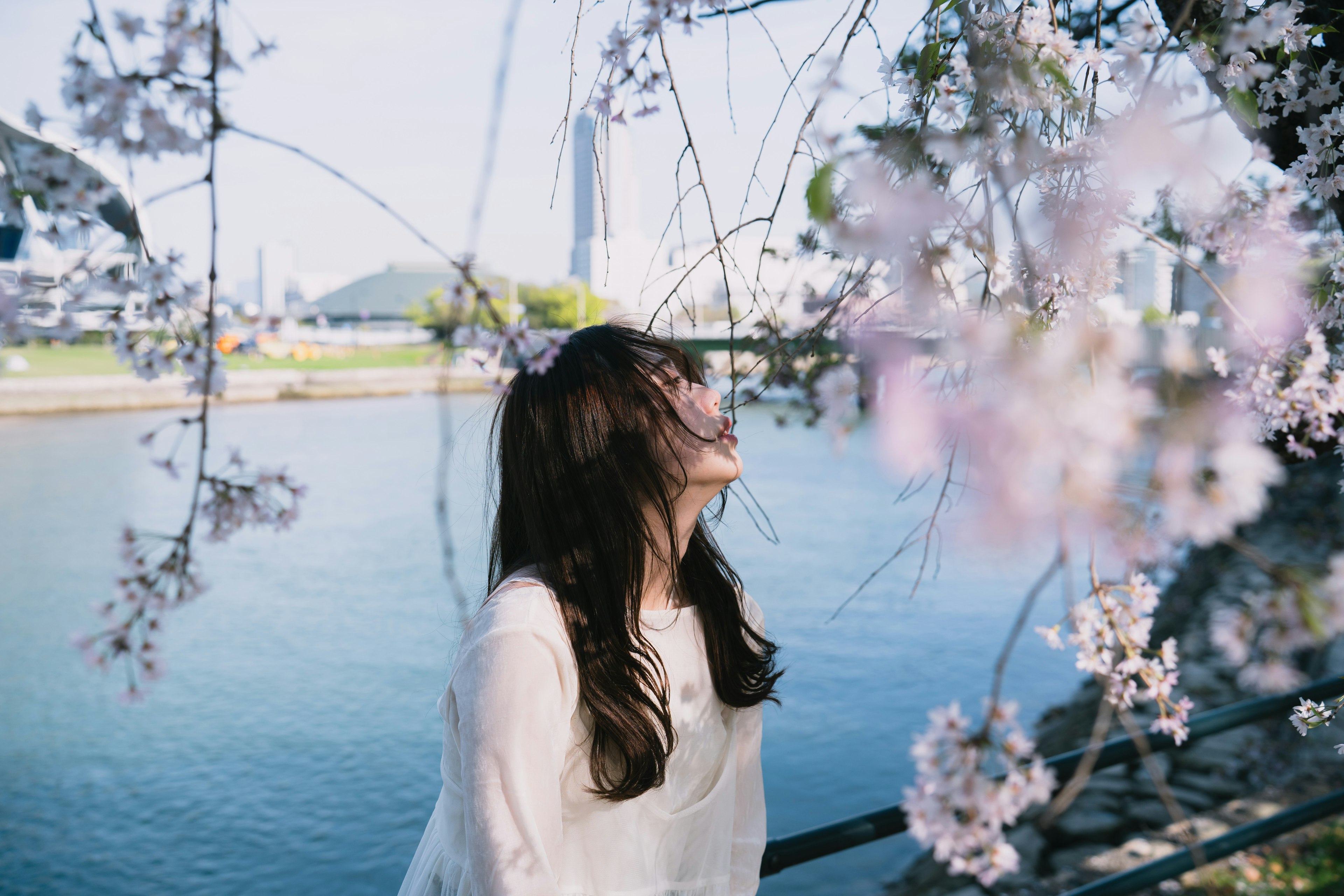 Ritratto di una donna che sorride sotto un albero di ciliegio vicino al fiume