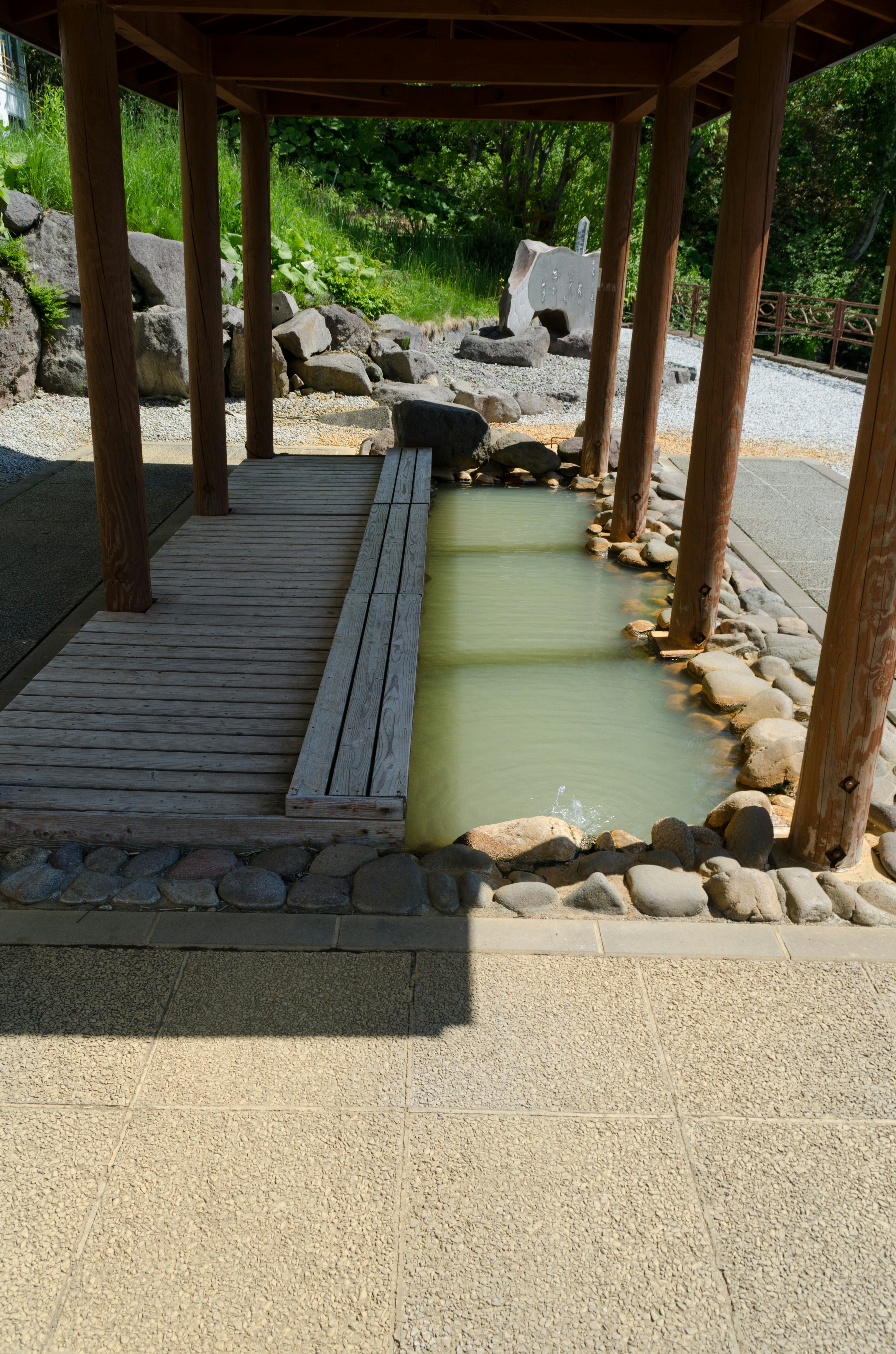 Panchina in legno e sorgente termale in un giardino tranquillo