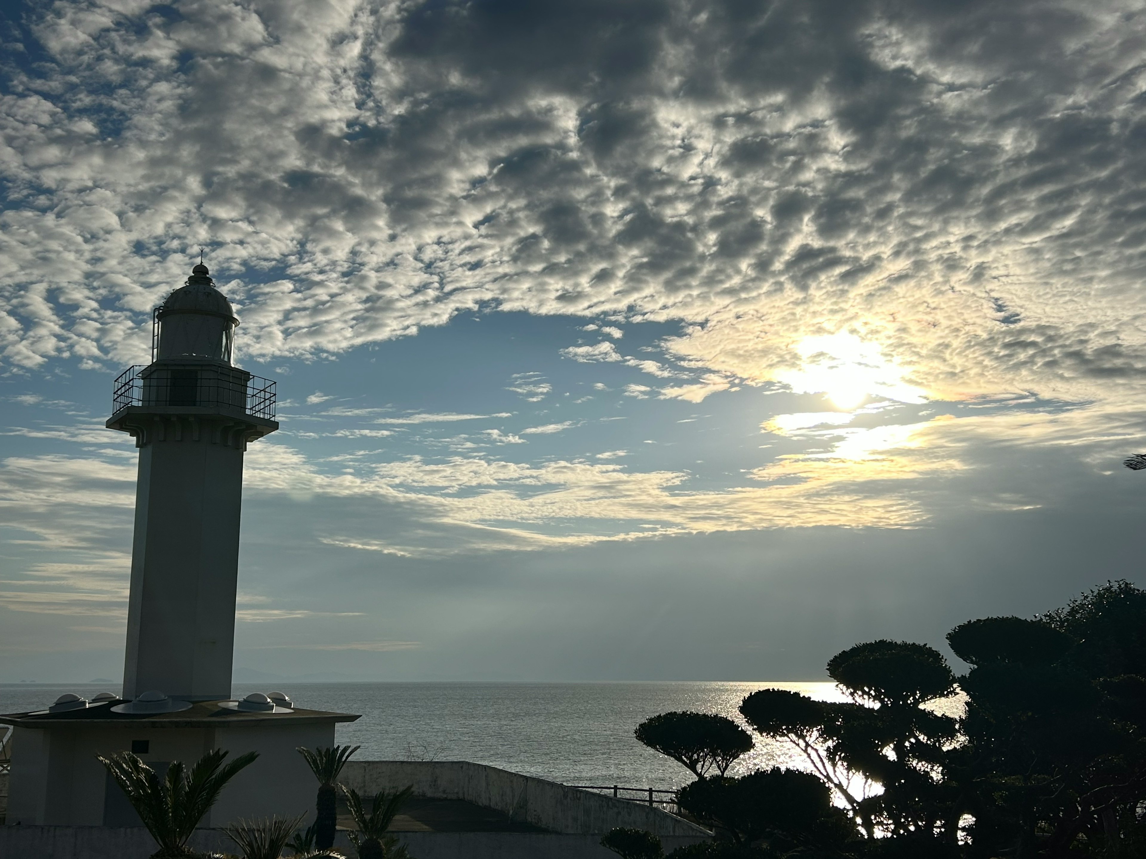 Vista panoramica di un faro sul mare con un cielo drammatico e luce solare