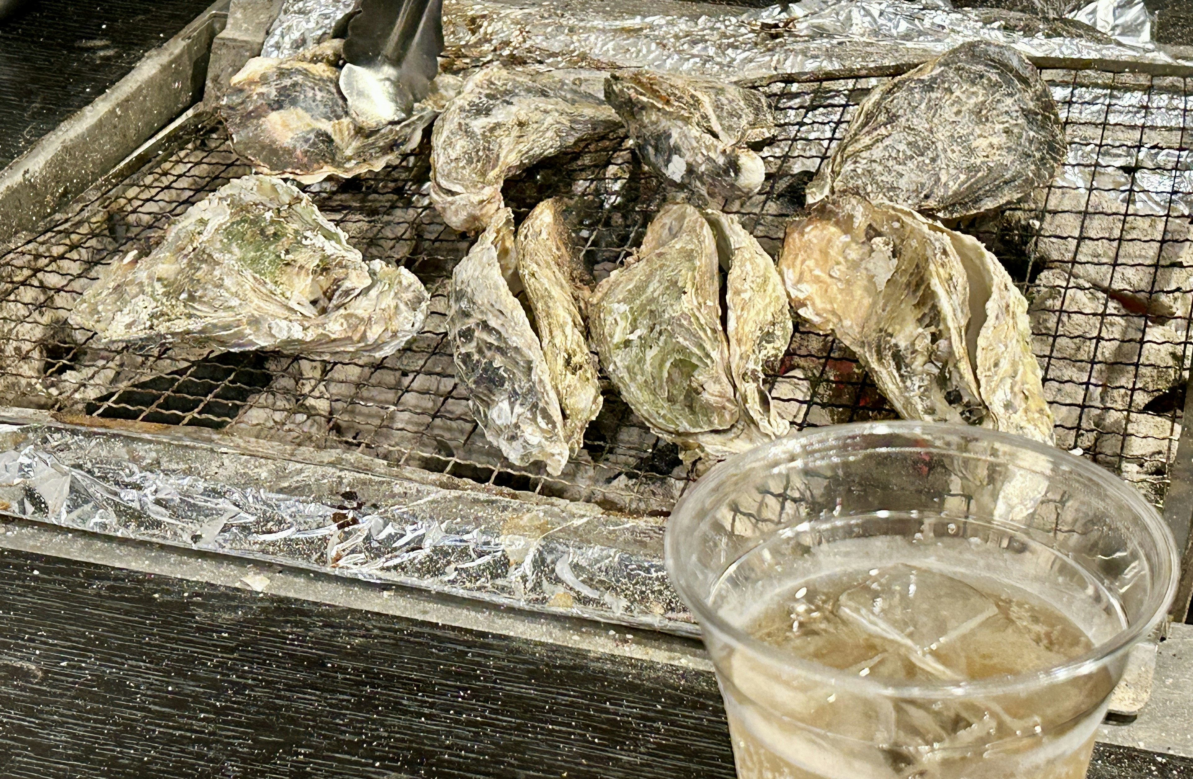 Grilled oysters on a wire rack with a drink nearby