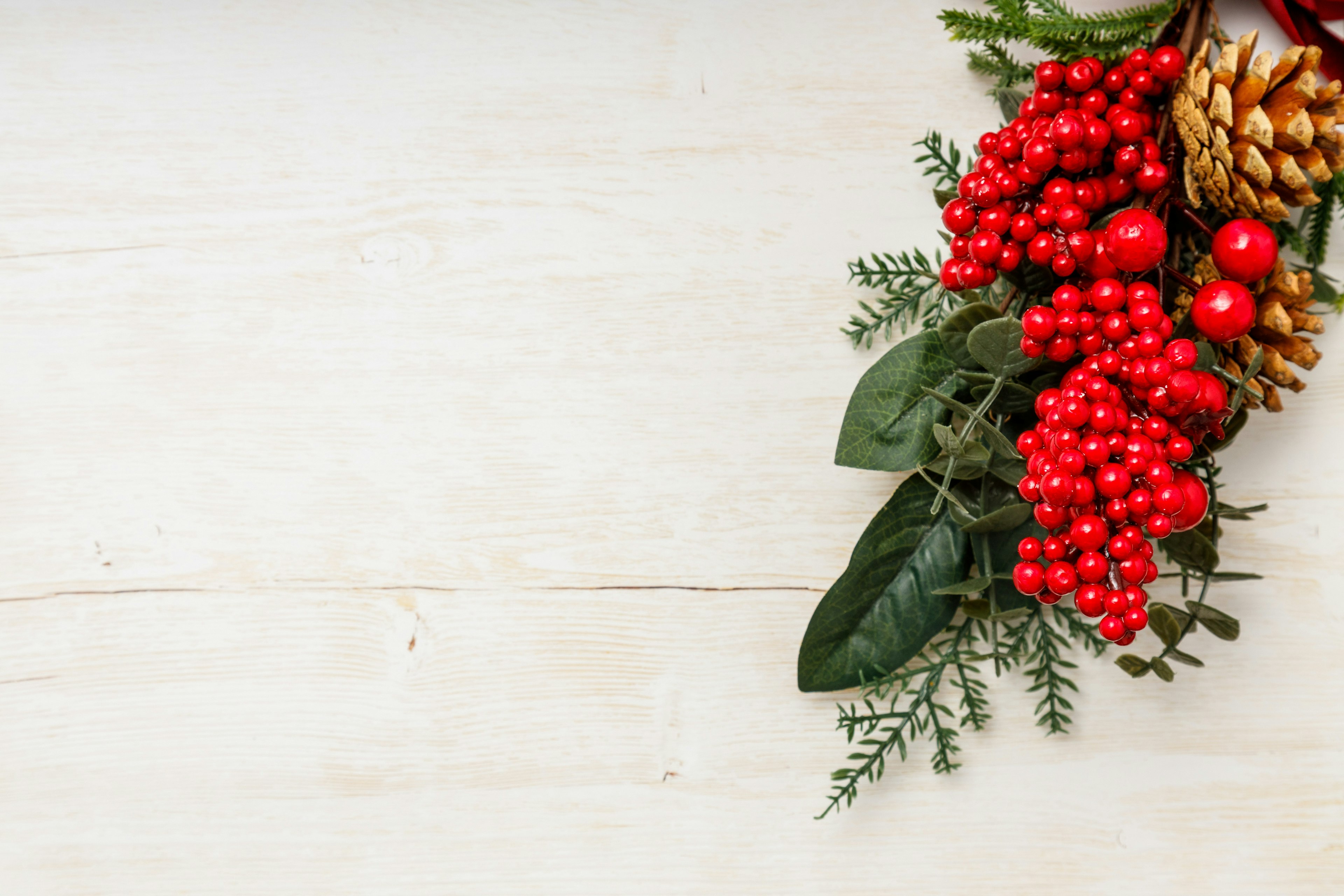 Weihnachtliche Blumenarrangement mit roten Beeren und Tannenzapfen