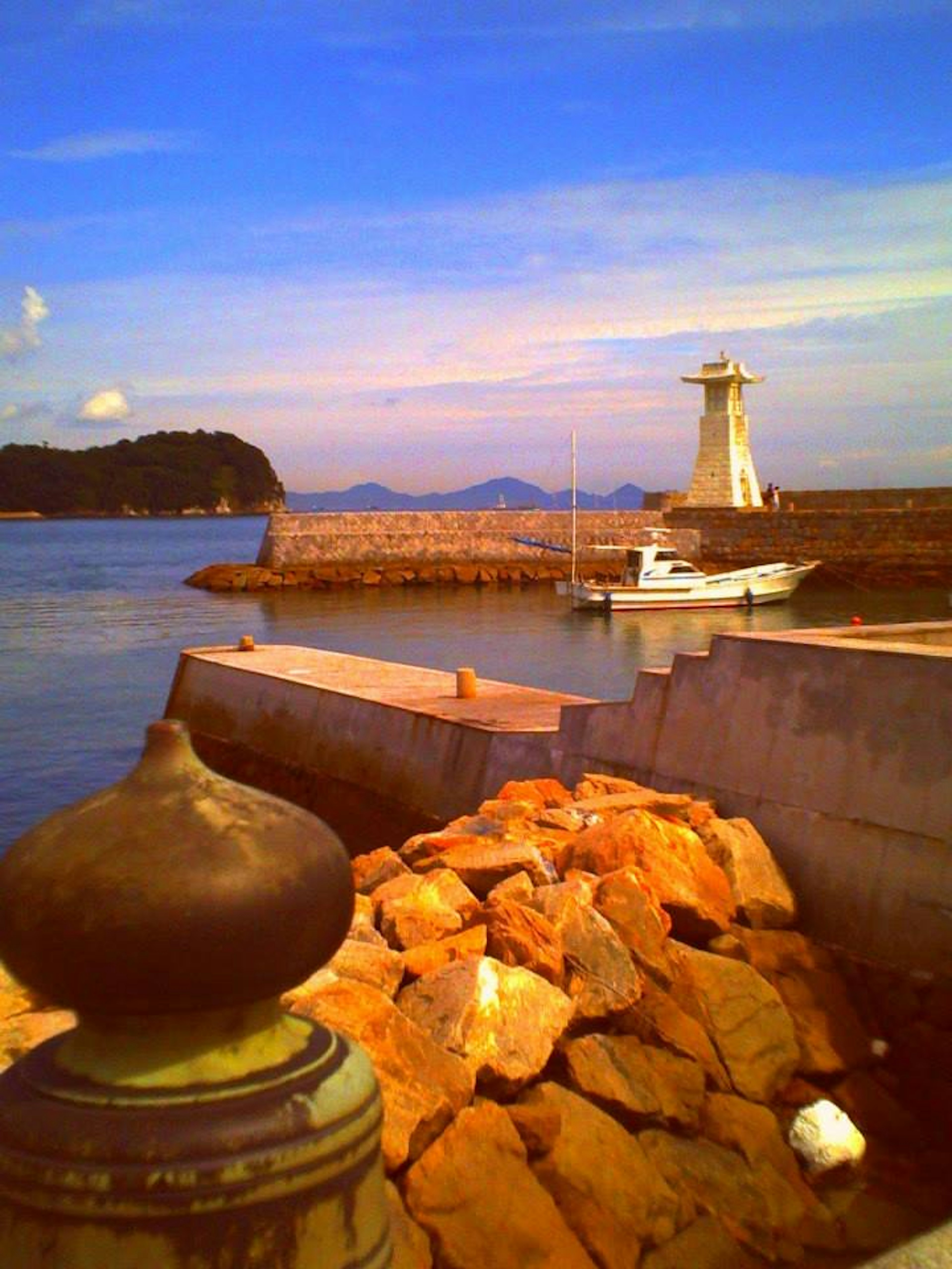 Scenic view of a coastline with a lighthouse and a boat moored