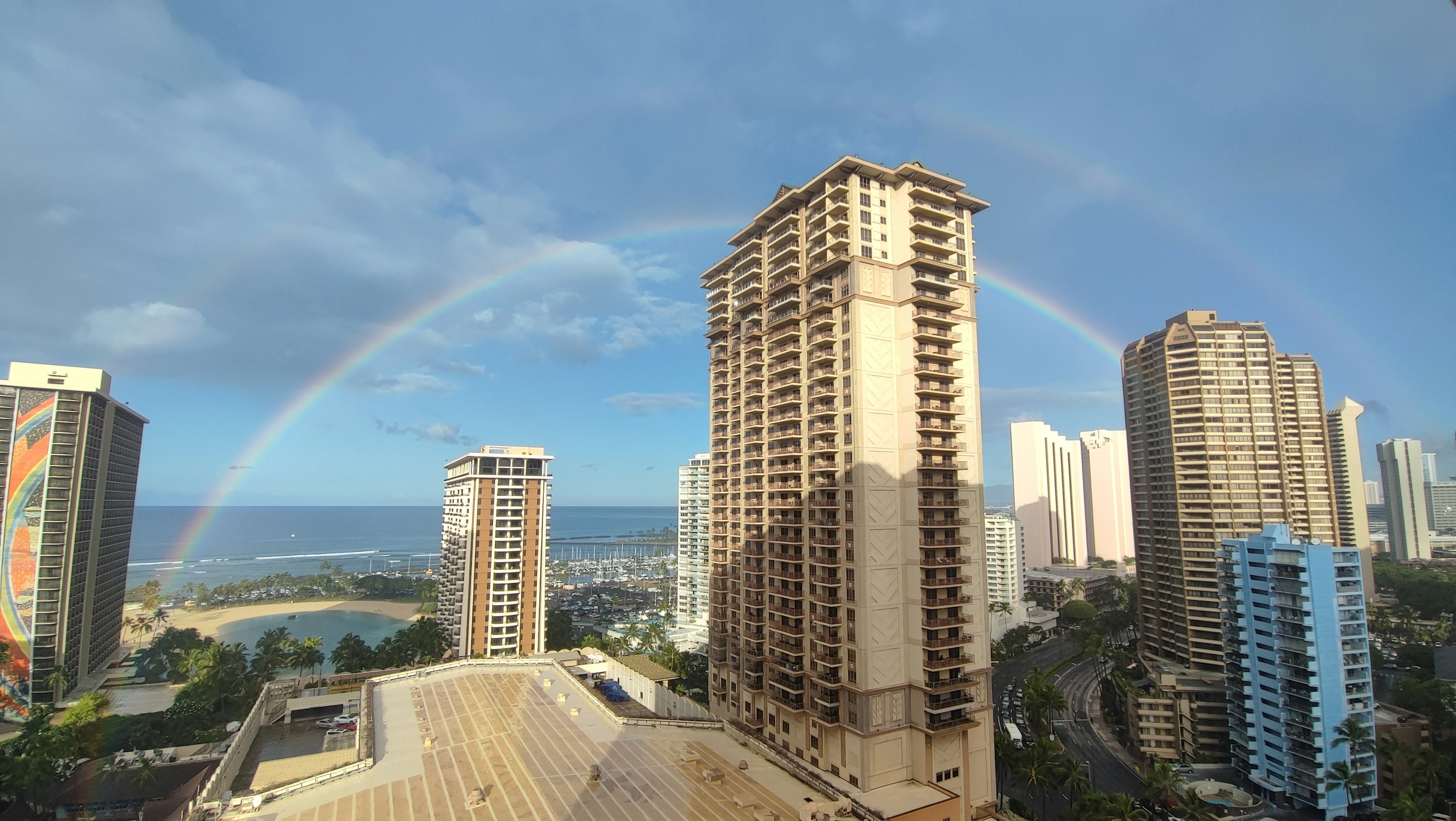 ハワイの高層ビルの間に架かる虹と青空