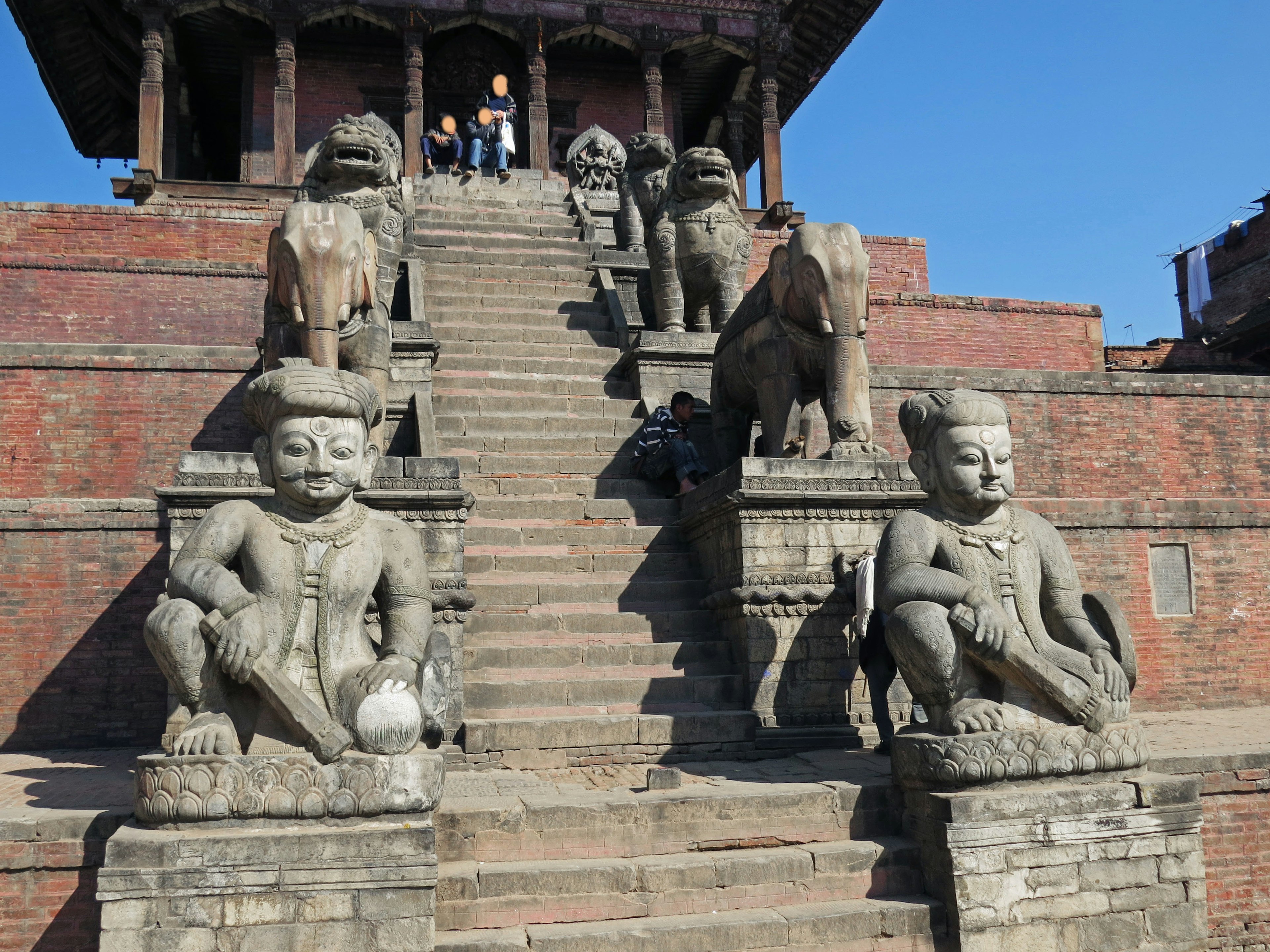 Stone statues on either side of a staircase leading to a temple