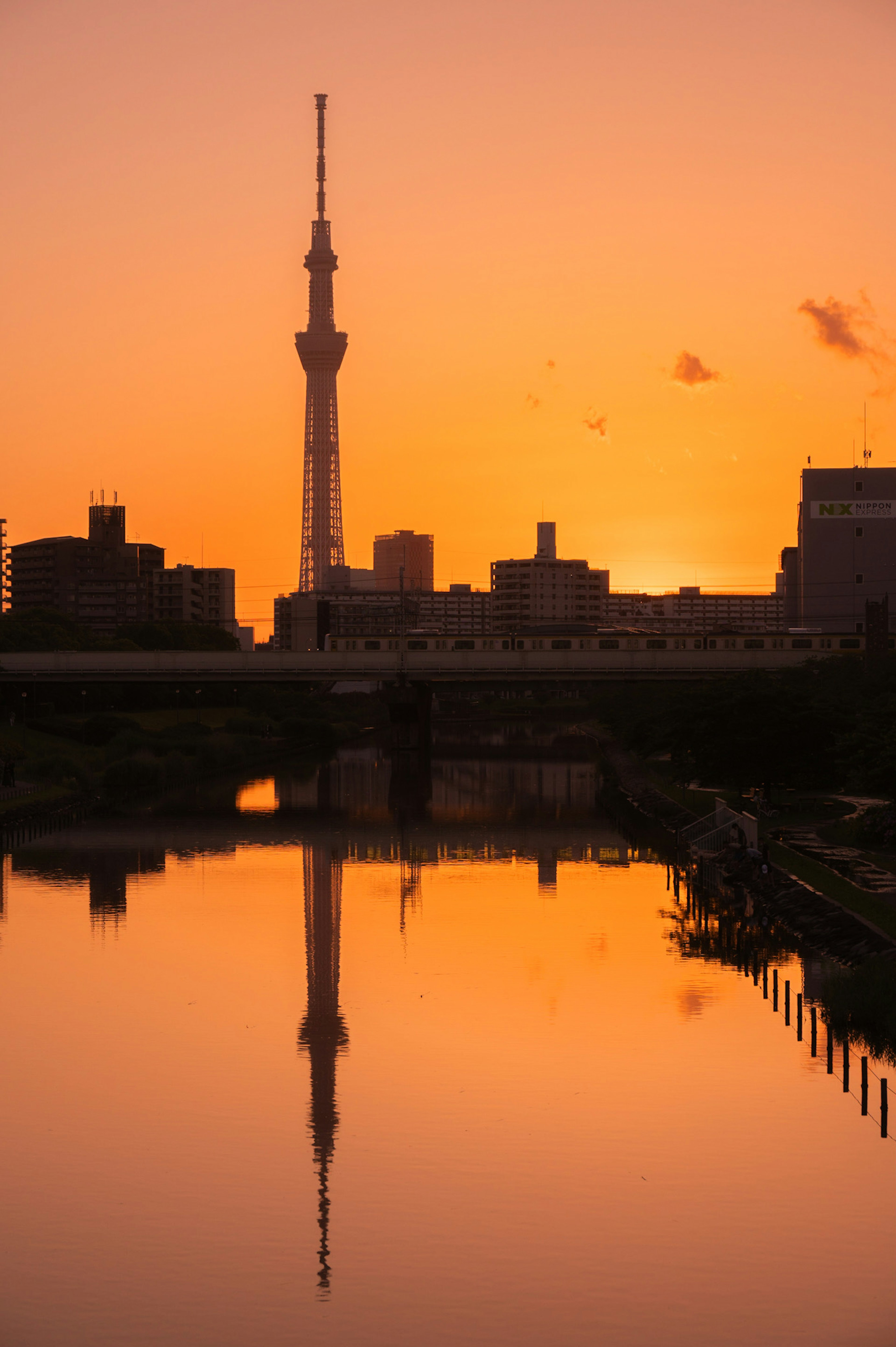 Siluet Tokyo Skytree di latar belakang matahari terbenam dengan pantulan di air