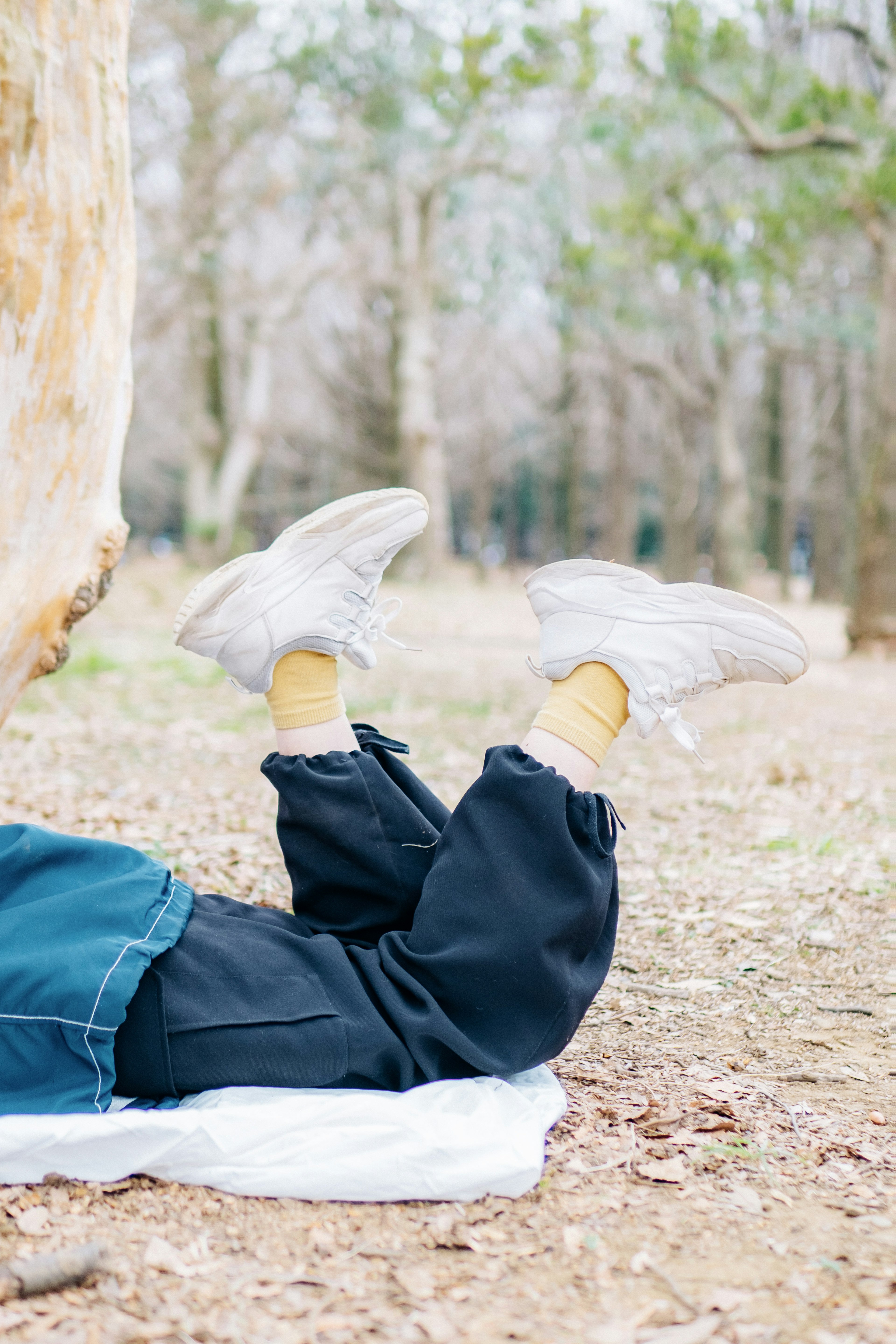 Child's feet in white sneakers resting outdoors in a forest