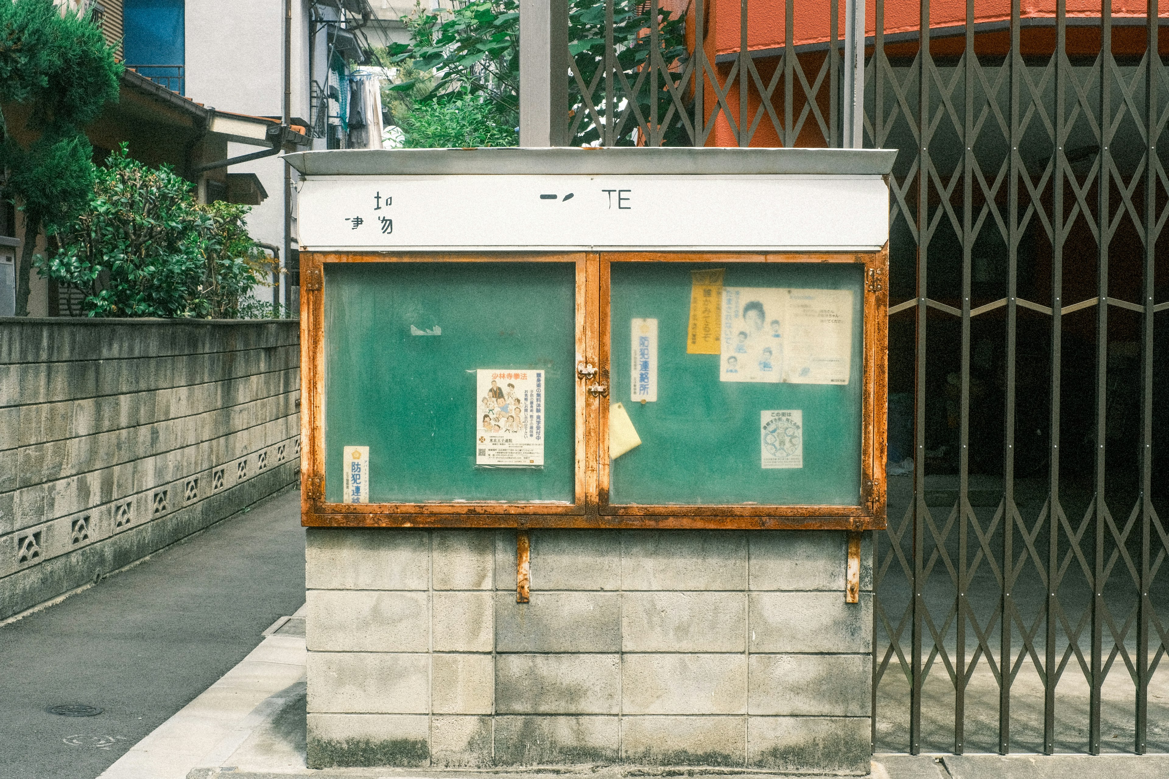 길모퉁이에 있는 오래된 게시판 녹색 벽과 벗겨진 포스터가 특징