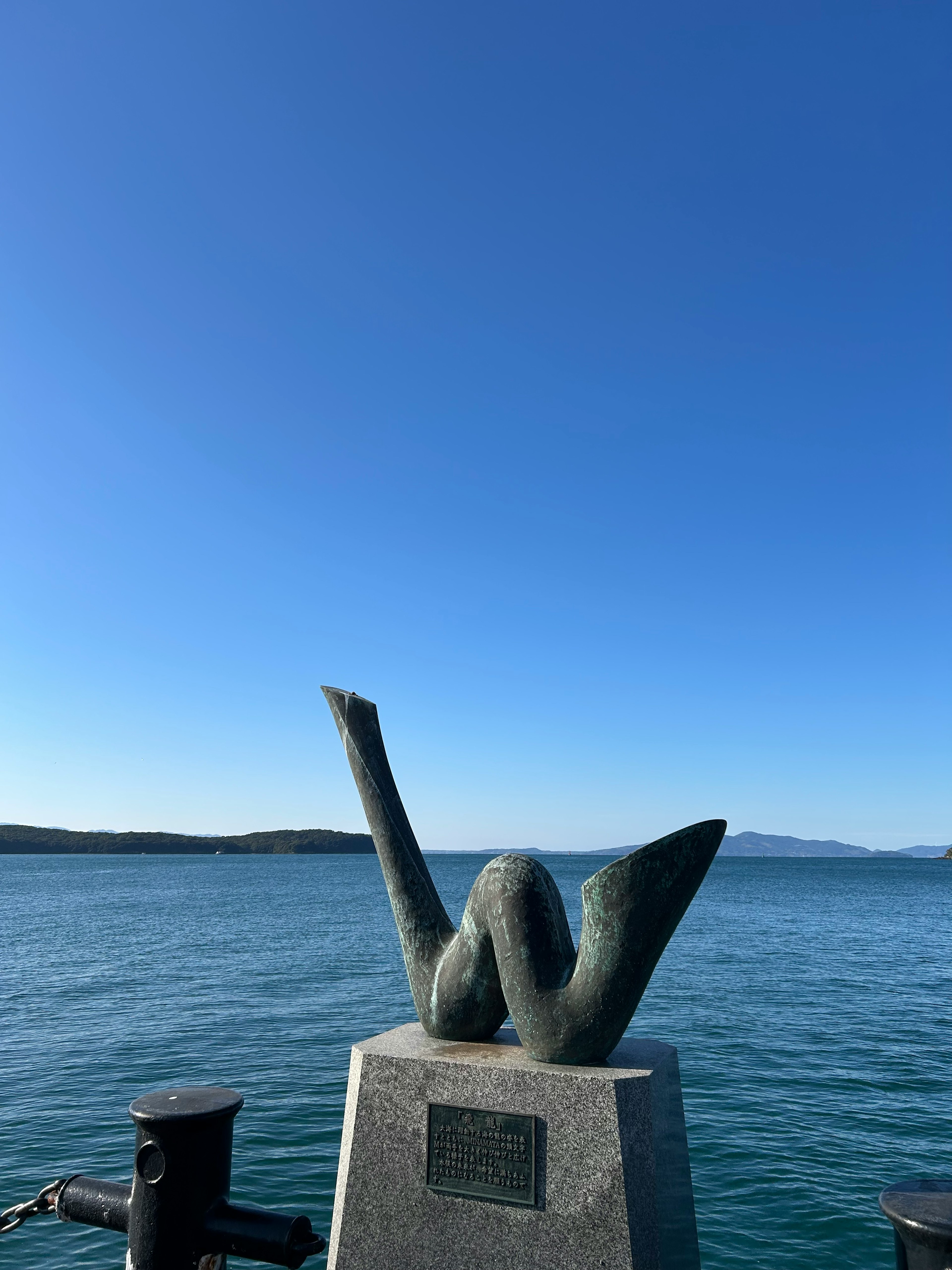 Escultura artística con fondo de cielo azul y agua