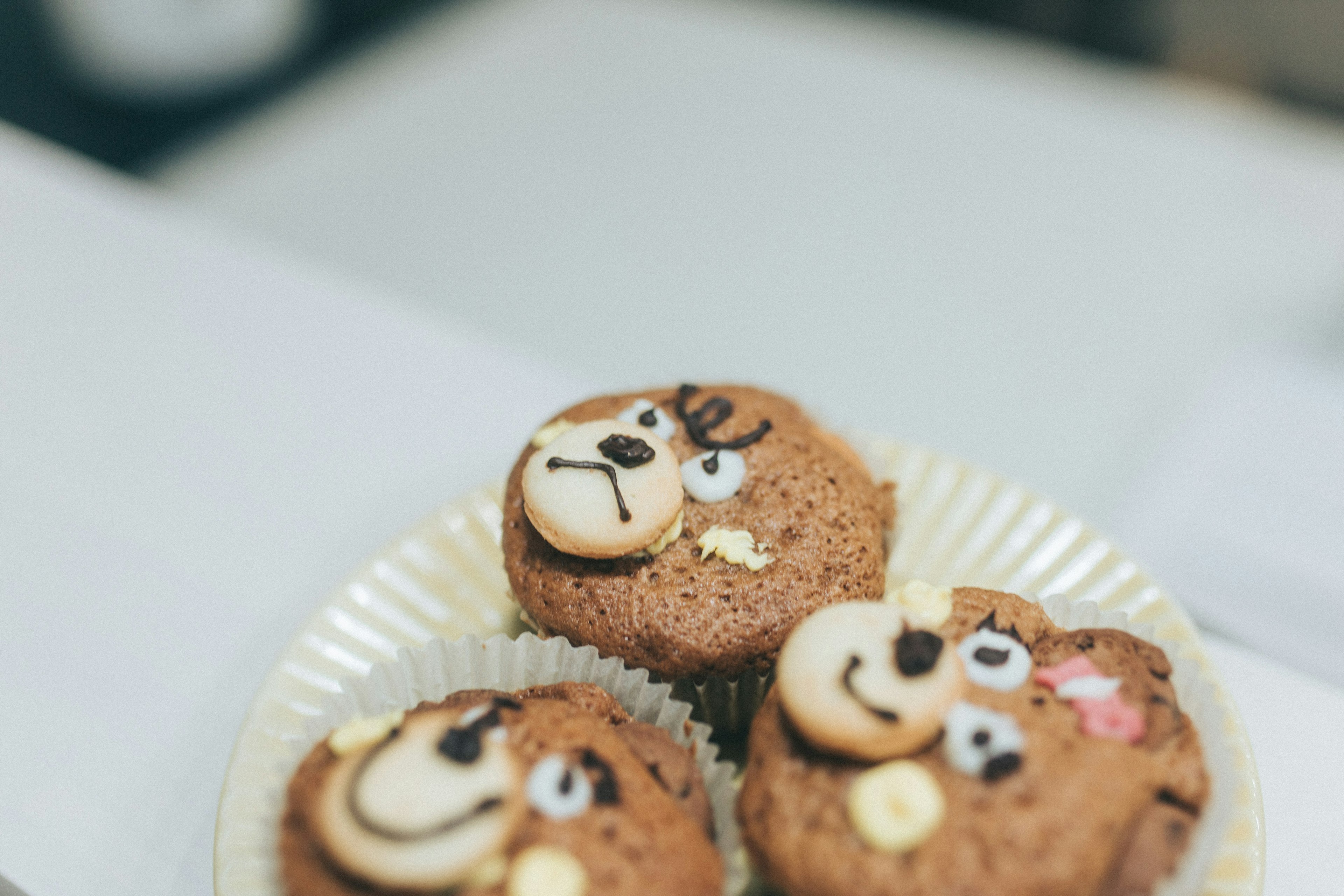 Plate of chocolate muffins decorated with cute animal faces