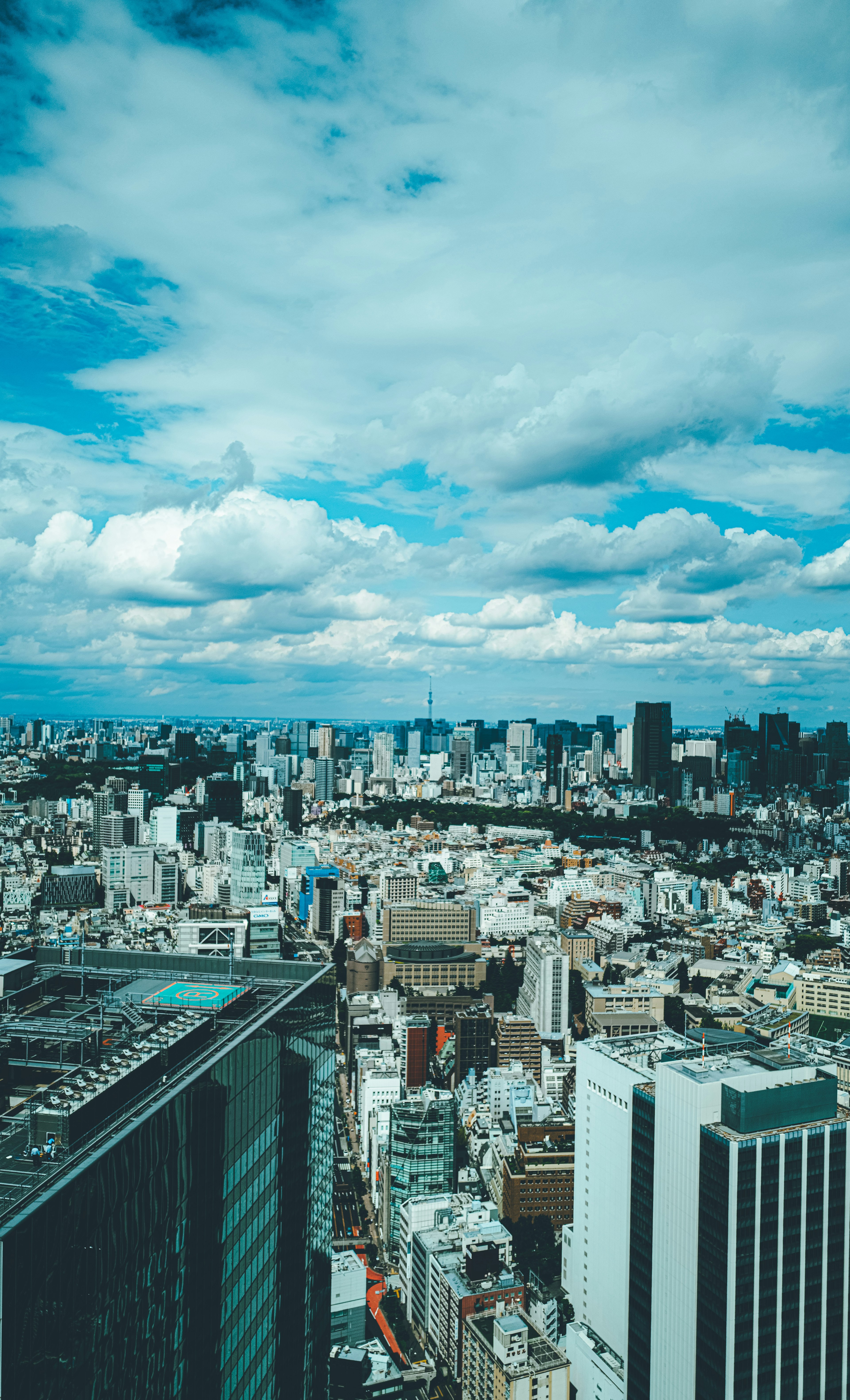 Vue panoramique d'une ville avec ciel bleu et nuages comprenant des immeubles de grande hauteur et des zones résidentielles