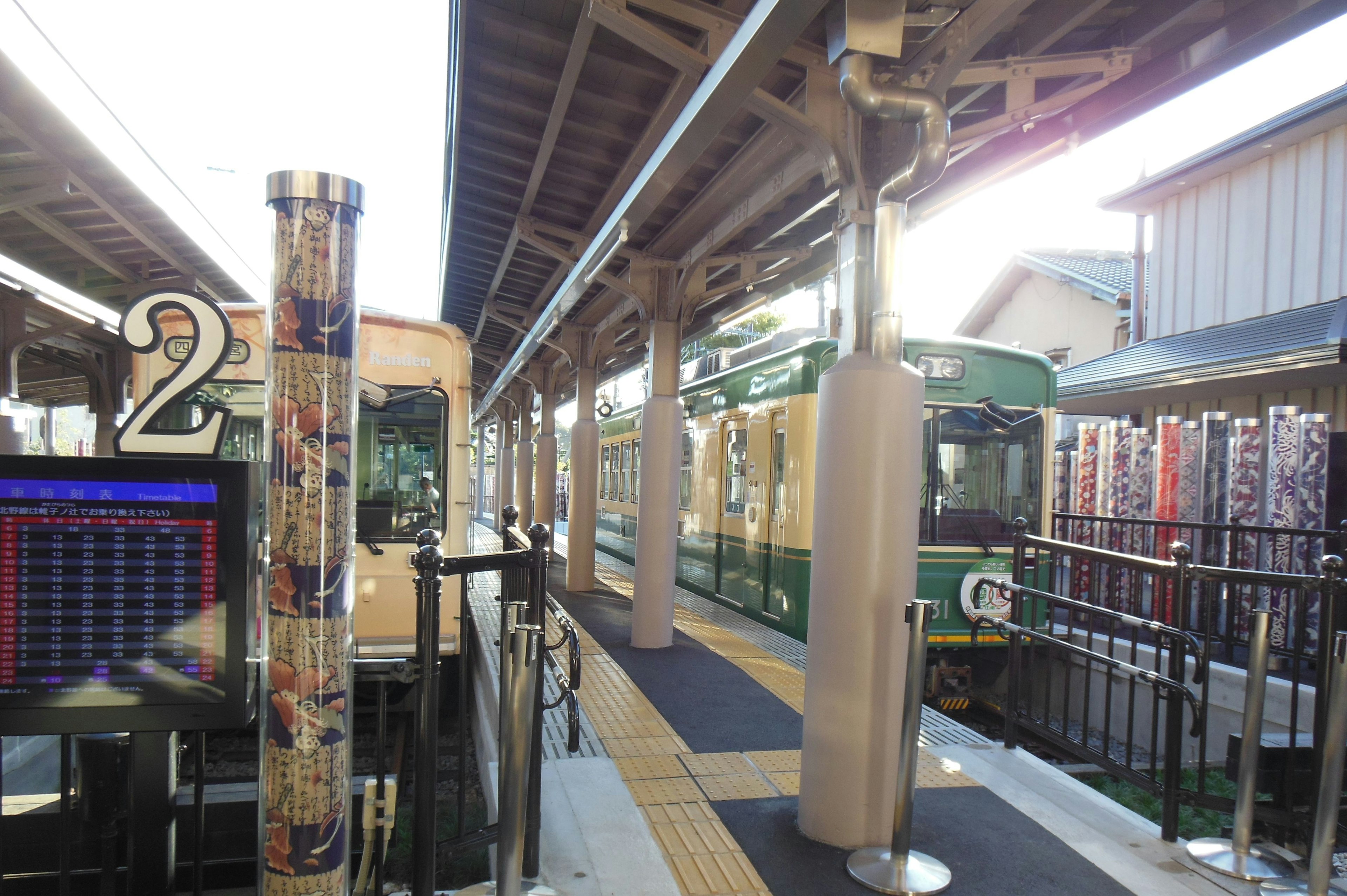 Tren verde en una plataforma de estación con el poste número 2