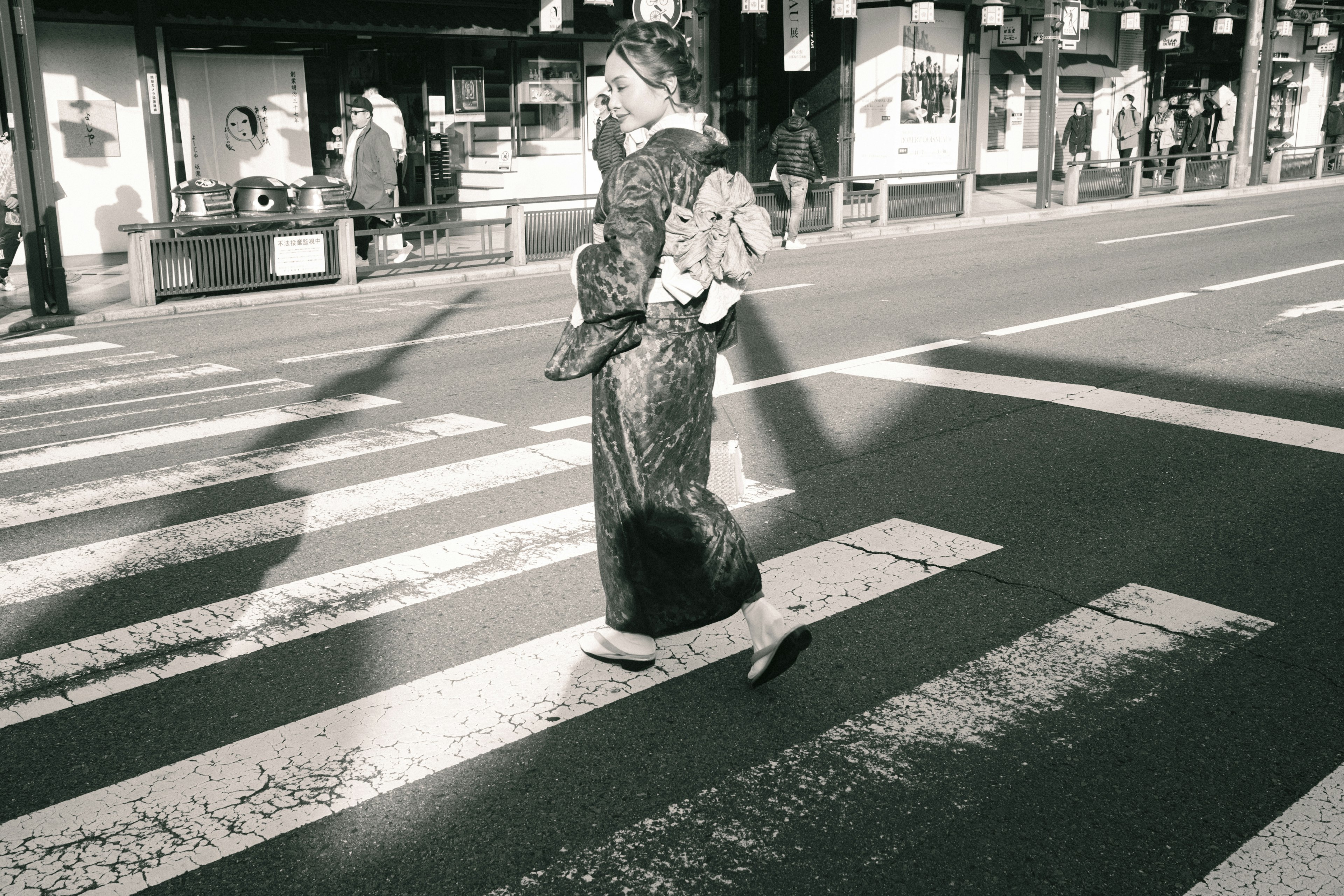 Woman in kimono crossing a black and white crosswalk