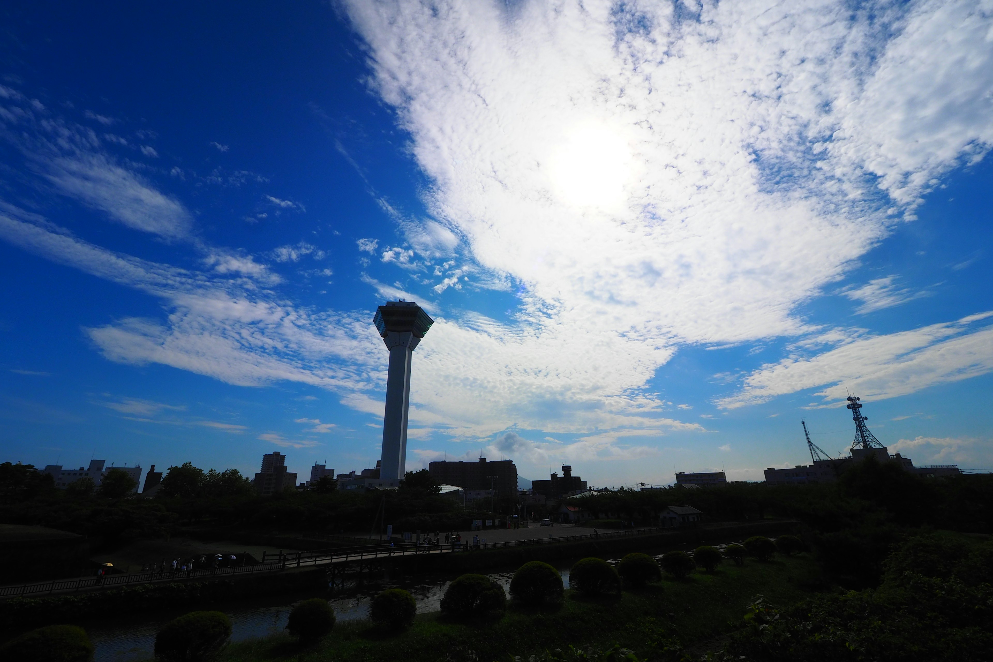 Pemandangan dengan menara air di latar belakang langit biru dan awan putih